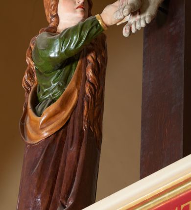 Zdjęcie nr 3: Grupa Ukrzyżowania złożona z ukrzyżowanego Chrystusa w typie christo vivo, stojących postaci Matki Boskiej i św. Jana oraz klęczącej Marii Magdaleny. Figura Chrystusa jest rzeźbą pełnoplastyczną, nieznacznie ściętą z tyłu, pozostałe są ścięte i wydrążone od tyłu. Zbawiciel przybity trzema gwoździami, z niemal prosto rozpostartymi rękami, z głową przechyloną na prawe ramię. Jego twarz jest pociągła, nos długi, oczy otwarte, twarz okolona kręconą, brązową brodą na głowie kręcone, sięgające szyi włosy i korona cierniowa pomalowana na zielono. Ręce z wyłamanymi barkami, z uwidocznionymi ścięgnami, klatka piersiowa wybrzuszona, z widocznymi żebrami i mostkiem, nogi smukłe z wyeksponowanymi kośćmi i mięśniami. Złocone perizonium przepasane podwójnym sznurem, z dwiema swobodnie rozwianymi połami po obu stronach bioder. Na naturalistycznie oddanym ciele zaznaczone strużki krwi. Na górnej belce titulus z literami: INRI". 
Matka Boska przedstawiona w pozycji stojącej, w kontrapoście, z rękami skrzyżowanymi na piersi. Głowę zwraca w kierunku Chrystusa, jej twarz jest owalna, włosy długie, brązowe, opadające na ramiona. Ubrana jest w czerwoną suknię z żółtą lamówką na rękawach, niebieski płaszcz o żółtym podbiciu i białą, długą chustę na głowie.    
Święty Jan ukazany w pozycji stojącej, w kontrapoście, z rękami złożonymi w geście modlitwy. Jego twarz jest owalna, oczy szeroko otwarte, włosy brązowe, kręcone, opadające na ramiona. Apostoł jest ubrany w zieloną tunikę i czerwony płaszcz z pomarańczowym podbiciem, przewieszony przez lewe ramię i ugiętą rękę. 
Po prawej stronie krzyża klęczy Maria Magdalena, ukazana prawym profilem, z prawą ręką, w której trzyma gąbkę wyciągniętą ku krzyżowi. Jej twarz jest pociągła z prostym nosem, włosy jasnobrązowe, długie, kręcone, opadające na plecy. Jest ubrana w zieloną tunikę i brązowy płaszcz o jaśniejszym podbiciu, opadający z lewego ramienia.
Na belce w kolorze czerwonym złocony napis: "Benedictus XVI SPE SALVI FACTI SUMUS A(NNO) D(OMINI) MMVII".
