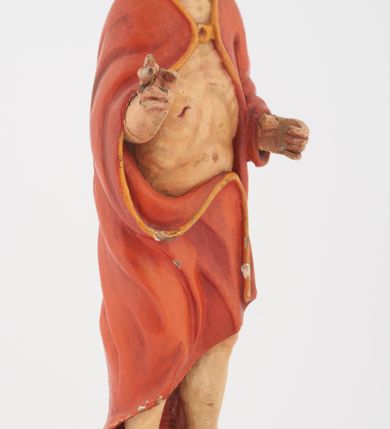 Zdjęcie nr 4: Pełnoplastyczna rzeźba Chrystusa Zmartwychwstałego stojącego na chmurze z prawą ręką wzniesioną w geście błogosławieństwa, lewą trzymającego krzyż na długim drzewcu. Twarz szeroka, z wydatnym nosem, ciemnobrązowymi oczami, ciemnoróżowymi ustami, okolona zarostem oraz włosami z przedziałkiem pośrodku głowy, opadającymi na plecy. Karnacja jasnobeżowa. Chrystus ukazany nagi, przesłonięty czerwonym płaszczem, spiętym na piersi, opadającym ukośnymi fałdami do ziemi. 