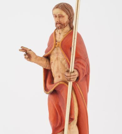 Zdjęcie nr 2: Pełnoplastyczna rzeźba Chrystusa Zmartwychwstałego stojącego na chmurze z prawą ręką wzniesioną w geście błogosławieństwa, lewą trzymającego krzyż na długim drzewcu. Twarz szeroka, z wydatnym nosem, ciemnobrązowymi oczami, ciemnoróżowymi ustami, okolona zarostem oraz włosami z przedziałkiem pośrodku głowy, opadającymi na plecy. Karnacja jasnobeżowa. Chrystus ukazany nagi, przesłonięty czerwonym płaszczem, spiętym na piersi, opadającym ukośnymi fałdami do ziemi. 