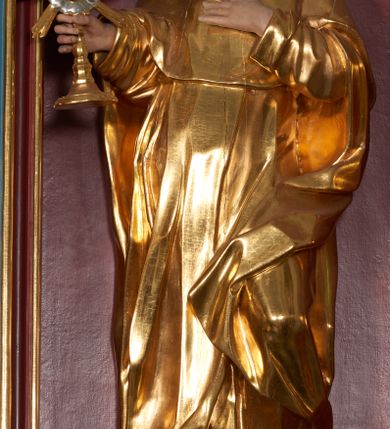 Zdjęcie nr 2: Rzeźba przyścienna, całopostaciowa, zapewne drążona od tyłu. Święty jest ujęty w lekkim kontrapoście, z ugiętą lewą nogą. Jego lewa ręka jest zgięta w łokciu i złożona na piersi, w prawej trzyma monstrancję. Głowa jest zwrócona w prawo i lekko pochylona, twarz o ostrych rysach, prostym nosie, małych oczach. Na głowie tonsura i brązowe, krótkie włosy. Święty jest ubrany w habit dominikański i płaszcz z kapturem zarzucony na lewe kolano, spod habitu wystają brązowe buty. Figura polichromowana naturalistycznie w partiach ciała ze złoconym strojem oraz złoconą i srebrzoną monstrancją.
