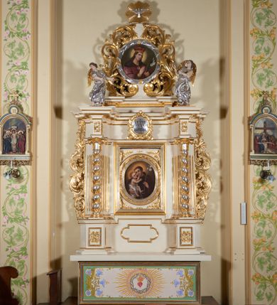 Zdjęcie nr 1: Ołtarz architektoniczny, jednokondygnacyjny, jednoosiowy, ze zwieńczeniem. Mensa drewniana, antepedium drewniane, nowe, z malowanym gorejącym sercem otoczonym koroną cierniową i promienistą glorią. Retabulum na niewysokim cokole z uskokowymi postumentami, ujęte parą półfilarów o żłobkowanych trzonach i ustawionych na ich tle kolumn o spiralnie skręconych trzonach, wspierających wyłamujące się ponad nimi belkowanie z silnie wysuniętym gzymsem. Boki ołtarza ujęte akantowymi liśćmi, srebrzone trzony kolumn przeplecione złoconymi liśćmi. W centrum prostokątna wnęka w profilowanej ramie z owalnym obrazem z przedstawieniem św. Antoniego z Dzieciątkiem. Nad wnęką kartusz z napisem: „JEZU / UFAM / TOBIE”. Zwieńczenie utworzone z okrągłego obrazu z wizerunkiem św. Kazimierza w srebrzonej ramie na kształt wieńca laurowego obwiedzionego liśćmi akantu, które przechodzą dołem w karbowaną wstęgę regencyjną; w górnej części zwieńczenia gołębica Ducha Świętego na tle promieni. Po bokach zwieńczenia dwa stojące anioły. Struktura polichromowana w kolorze jasnego beżu, ornamentyka i partie detalu architektonicznego złocone i srebrzone.   

