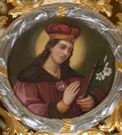 Zdjęcie nr 1: Obraz okrągły, ujęty srebrzoną i złoconą ramą w formie wieńca laurowego oraz szerokim, ażurowym obramieniem utworzonym z suchego akantu. Święty Kazimierz ujęty półpostaciowo, w trzech czwartych zwrócony w lewo, z głową lekko pochyloną w dół. Jego twarz jest pociągła o delikatnych, młodzieńczych rysach, włosy długie, kręcone, ciemnobrązowe, opadające na plecy i ramiona. Ubrany w ciemoczerwony płaszcz książęcy, spod którego pod szyją wystaje fragment żółtego kaftana, a na rękach – rękawy; na głowie nosi mitrę książęcą. Płaszcz jest ciemnoczerwony, ma szeroki futrzany kołnierz i mankiety. Spięty jest na piersiach złotą zapinką z herbami Jagiellonów – Pogonią i Orłem. W lewej dłoni święty trzyma krucyfiks i białą lilię, a prawą unosi na wysokości klatki piersiowej. Wokół jego głowy świetlisty nimb. Tło jednolite, ciemnobrązowe. Kolorystyka o stonowanym nasyceniu, przyciemniona. 

