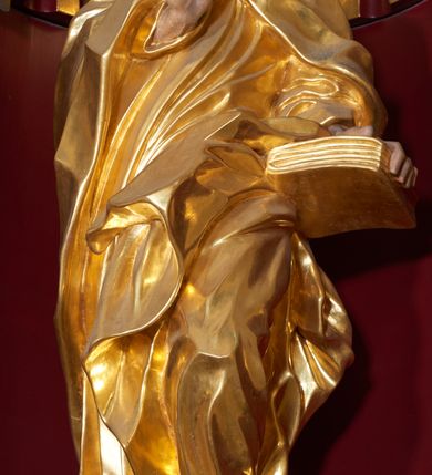 Zdjęcie nr 3: Święty Joachim został ukazany frontalnie, całopostaciowo, w lekkim kontrapoście, z prawą ręką wyciągniętą na piersi w geście błogosławieństwa, a lewą przytrzymującą księgę wspartą na biodrze. Jest ubrany w długą suknię i płaszcz spięty na piersi, okrywający plecy i przerzucony przez lewą nogę. Twarz o wydatnych policzkach, z głębokimi oczodołami, masywnym nosie i otwartymi ustami. Włosy krótkie, kręcone, układane w pojedyncze pukle; broda jest krótka, falująca.  
