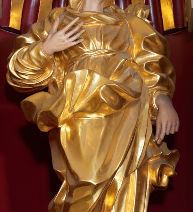 Zdjęcie nr 4: Święta Anna została ukazana frontalnie, całopostaciowo, w lekkim kontrapoście, z prawą ręką zgiętą w łokciu i uniesioną na wysokości piersi, a lewą opuszczoną wzdłuż ciała. Ubrana w długą suknię przewiązaną, płaszcz zarzucony na plecy i welon na głowie. Ma twarz o ostrych rysach, z wydatnymi kościami policzkowymi, szerokim, dużym nosem, otwartymi oczami i zamkniętymi ustami. 