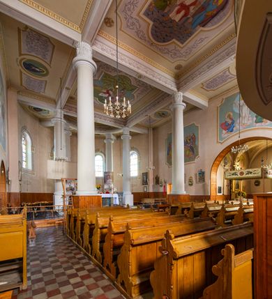 Zdjęcie nr 22: Kościół murowany z cegły na niskiej, kamiennej podmurówce, orientowany, jednonawowy ze zredukowanym transeptem oraz nieco niższym, zamkniętym półkoliście prezbiterium. Do północno-wschodniego narożnika nawy (przy prezbiterium) przylega założona na rzucie prostokąta, oszkarpowana zakrystia dostępna półkolistym portalem od strony północnej. Do południowo-wschodniego narożnika nawy dostawiona kaplica Matki Boskiej na rzucie prostokąta zamknięta od wschodu niewielką absydą. Ramiona transeptu zredukowane do roli prostokątnych kaplic. Do południowo-zachodniego i północno-zachodniego narożnika nawy dobudowane nowsze kruchty boczne założone na rzucie prostokąta dostępne portalami o półkolistym wykroju. Kruchta zachodnia na rzucie prostokąta dostępna nowym, prostokątnym wejściem. W ścianach północnej i południowej widoczne, zamurowane, starsze otwory wejściowe (od południa w miejsce portalu okrągłe okno). Dach nad nawą dwuspadowy z trzecią połacią zakrywającą ścianę szczytową; w części wschodniej wieloboczna wieżyczka na sygnaturkę z glorietą zwieńczoną krzyżem. Kruchty oraz kaplice boczne kryte dachami trójpołaciowymi, prezbiterium jednopołaciowym; nad zakrystią dach mansardowy z prostokątnym oknem w lukarnie. Pokrycia dachowe wykonane są z blachy (pierwotnie była to czerwona dachówka). W nawie i prezbiterium strop o konstrukcji żelbetowej wsparty na dziewięciu masywnych kolumnach ustawionych na wysokich cokołach; kaplice boczne sklepione krzyżowo, w zakrystii założony betonowy strop. Chór muzyczny murowany, wsparty na pierwszej od zachodu parze kolumn dźwigających strop. Fasada jednokondygnacyjna, trójosiowa z umieszczoną w osi centralnej prostopadłościenną kruchtą mieszczącą prostokątny otwór wejściowy (nowy). Okna w kształcie stojącego prostokąta o smukłych proporcjach, zamknięte półkoliście. Okno środkowe, umieszczone nieco wyżej, niższe od pozostałych. W ścianach zachodnich krucht bocznych po jednym niewielkim oknie o wykroju półkolistym. Trójkątna ściana szczytowa zasłonięta blaszanym dachem o przełamanej w dolnej części połaci, zwieńczona niewielkim, metalowym krzyżem. Elewacje boczne jednokondygnacyjne, o nieregularnym przebiegu osi. W elewacji południowej w pierwszej osi ceglany portal z nadświetlem o wykroju półkolistym, w drugiej okrągłe okno doświetlające kaplicę boczną, w kolejnych: półkolisty ceglany portal do zakrystii oraz okno o półkolistym wykroju z motywem biforium. W elewacji północnej w osi pierwszej i drugiej niewielkie półkoliście wykrojone okna, w osi trzeciej okrągłe okno doświetlające kaplicę, w osi czwartej natomiast ceglany portal  z nadświetlem o wykroju półkolistym. W prezbiterium cztery okna o wykroju półkolistym. W trzeciej osi, pomiędzy oknami, ujęta wielobocznymi filarami dźwigającymi, wydatny, profilowany gzyms tynkowana na biało nisza z figurą Matki Boskiej Fatimskiej umieszczonej pod baldachimem. Górną część murów nawy, prezbiterium, zakrystii, kaplic oraz obu krucht bocznych obiega profilowany gzyms okapowy. 