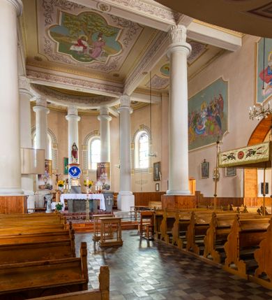 Zdjęcie nr 19: Kościół murowany z cegły na niskiej, kamiennej podmurówce, orientowany, jednonawowy ze zredukowanym transeptem oraz nieco niższym, zamkniętym półkoliście prezbiterium. Do północno-wschodniego narożnika nawy (przy prezbiterium) przylega założona na rzucie prostokąta, oszkarpowana zakrystia dostępna półkolistym portalem od strony północnej. Do południowo-wschodniego narożnika nawy dostawiona kaplica Matki Boskiej na rzucie prostokąta zamknięta od wschodu niewielką absydą. Ramiona transeptu zredukowane do roli prostokątnych kaplic. Do południowo-zachodniego i północno-zachodniego narożnika nawy dobudowane nowsze kruchty boczne założone na rzucie prostokąta dostępne portalami o półkolistym wykroju. Kruchta zachodnia na rzucie prostokąta dostępna nowym, prostokątnym wejściem. W ścianach północnej i południowej widoczne, zamurowane, starsze otwory wejściowe (od południa w miejsce portalu okrągłe okno). Dach nad nawą dwuspadowy z trzecią połacią zakrywającą ścianę szczytową; w części wschodniej wieloboczna wieżyczka na sygnaturkę z glorietą zwieńczoną krzyżem. Kruchty oraz kaplice boczne kryte dachami trójpołaciowymi, prezbiterium jednopołaciowym; nad zakrystią dach mansardowy z prostokątnym oknem w lukarnie. Pokrycia dachowe wykonane są z blachy (pierwotnie była to czerwona dachówka). W nawie i prezbiterium strop o konstrukcji żelbetowej wsparty na dziewięciu masywnych kolumnach ustawionych na wysokich cokołach; kaplice boczne sklepione krzyżowo, w zakrystii założony betonowy strop. Chór muzyczny murowany, wsparty na pierwszej od zachodu parze kolumn dźwigających strop. Fasada jednokondygnacyjna, trójosiowa z umieszczoną w osi centralnej prostopadłościenną kruchtą mieszczącą prostokątny otwór wejściowy (nowy). Okna w kształcie stojącego prostokąta o smukłych proporcjach, zamknięte półkoliście. Okno środkowe, umieszczone nieco wyżej, niższe od pozostałych. W ścianach zachodnich krucht bocznych po jednym niewielkim oknie o wykroju półkolistym. Trójkątna ściana szczytowa zasłonięta blaszanym dachem o przełamanej w dolnej części połaci, zwieńczona niewielkim, metalowym krzyżem. Elewacje boczne jednokondygnacyjne, o nieregularnym przebiegu osi. W elewacji południowej w pierwszej osi ceglany portal z nadświetlem o wykroju półkolistym, w drugiej okrągłe okno doświetlające kaplicę boczną, w kolejnych: półkolisty ceglany portal do zakrystii oraz okno o półkolistym wykroju z motywem biforium. W elewacji północnej w osi pierwszej i drugiej niewielkie półkoliście wykrojone okna, w osi trzeciej okrągłe okno doświetlające kaplicę, w osi czwartej natomiast ceglany portal  z nadświetlem o wykroju półkolistym. W prezbiterium cztery okna o wykroju półkolistym. W trzeciej osi, pomiędzy oknami, ujęta wielobocznymi filarami dźwigającymi, wydatny, profilowany gzyms tynkowana na biało nisza z figurą Matki Boskiej Fatimskiej umieszczonej pod baldachimem. Górną część murów nawy, prezbiterium, zakrystii, kaplic oraz obu krucht bocznych obiega profilowany gzyms okapowy. 