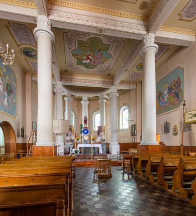 Zdjęcie nr 18: Kościół murowany z cegły na niskiej, kamiennej podmurówce, orientowany, jednonawowy ze zredukowanym transeptem oraz nieco niższym, zamkniętym półkoliście prezbiterium. Do północno-wschodniego narożnika nawy (przy prezbiterium) przylega założona na rzucie prostokąta, oszkarpowana zakrystia dostępna półkolistym portalem od strony północnej. Do południowo-wschodniego narożnika nawy dostawiona kaplica Matki Boskiej na rzucie prostokąta zamknięta od wschodu niewielką absydą. Ramiona transeptu zredukowane do roli prostokątnych kaplic. Do południowo-zachodniego i północno-zachodniego narożnika nawy dobudowane nowsze kruchty boczne założone na rzucie prostokąta dostępne portalami o półkolistym wykroju. Kruchta zachodnia na rzucie prostokąta dostępna nowym, prostokątnym wejściem. W ścianach północnej i południowej widoczne, zamurowane, starsze otwory wejściowe (od południa w miejsce portalu okrągłe okno). Dach nad nawą dwuspadowy z trzecią połacią zakrywającą ścianę szczytową; w części wschodniej wieloboczna wieżyczka na sygnaturkę z glorietą zwieńczoną krzyżem. Kruchty oraz kaplice boczne kryte dachami trójpołaciowymi, prezbiterium jednopołaciowym; nad zakrystią dach mansardowy z prostokątnym oknem w lukarnie. Pokrycia dachowe wykonane są z blachy (pierwotnie była to czerwona dachówka). W nawie i prezbiterium strop o konstrukcji żelbetowej wsparty na dziewięciu masywnych kolumnach ustawionych na wysokich cokołach; kaplice boczne sklepione krzyżowo, w zakrystii założony betonowy strop. Chór muzyczny murowany, wsparty na pierwszej od zachodu parze kolumn dźwigających strop. Fasada jednokondygnacyjna, trójosiowa z umieszczoną w osi centralnej prostopadłościenną kruchtą mieszczącą prostokątny otwór wejściowy (nowy). Okna w kształcie stojącego prostokąta o smukłych proporcjach, zamknięte półkoliście. Okno środkowe, umieszczone nieco wyżej, niższe od pozostałych. W ścianach zachodnich krucht bocznych po jednym niewielkim oknie o wykroju półkolistym. Trójkątna ściana szczytowa zasłonięta blaszanym dachem o przełamanej w dolnej części połaci, zwieńczona niewielkim, metalowym krzyżem. Elewacje boczne jednokondygnacyjne, o nieregularnym przebiegu osi. W elewacji południowej w pierwszej osi ceglany portal z nadświetlem o wykroju półkolistym, w drugiej okrągłe okno doświetlające kaplicę boczną, w kolejnych: półkolisty ceglany portal do zakrystii oraz okno o półkolistym wykroju z motywem biforium. W elewacji północnej w osi pierwszej i drugiej niewielkie półkoliście wykrojone okna, w osi trzeciej okrągłe okno doświetlające kaplicę, w osi czwartej natomiast ceglany portal  z nadświetlem o wykroju półkolistym. W prezbiterium cztery okna o wykroju półkolistym. W trzeciej osi, pomiędzy oknami, ujęta wielobocznymi filarami dźwigającymi, wydatny, profilowany gzyms tynkowana na biało nisza z figurą Matki Boskiej Fatimskiej umieszczonej pod baldachimem. Górną część murów nawy, prezbiterium, zakrystii, kaplic oraz obu krucht bocznych obiega profilowany gzyms okapowy. 