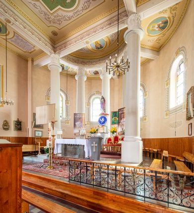 Zdjęcie nr 28: Kościół murowany z cegły na niskiej, kamiennej podmurówce, orientowany, jednonawowy ze zredukowanym transeptem oraz nieco niższym, zamkniętym półkoliście prezbiterium. Do północno-wschodniego narożnika nawy (przy prezbiterium) przylega założona na rzucie prostokąta, oszkarpowana zakrystia dostępna półkolistym portalem od strony północnej. Do południowo-wschodniego narożnika nawy dostawiona kaplica Matki Boskiej na rzucie prostokąta zamknięta od wschodu niewielką absydą. Ramiona transeptu zredukowane do roli prostokątnych kaplic. Do południowo-zachodniego i północno-zachodniego narożnika nawy dobudowane nowsze kruchty boczne założone na rzucie prostokąta dostępne portalami o półkolistym wykroju. Kruchta zachodnia na rzucie prostokąta dostępna nowym, prostokątnym wejściem. W ścianach północnej i południowej widoczne, zamurowane, starsze otwory wejściowe (od południa w miejsce portalu okrągłe okno). Dach nad nawą dwuspadowy z trzecią połacią zakrywającą ścianę szczytową; w części wschodniej wieloboczna wieżyczka na sygnaturkę z glorietą zwieńczoną krzyżem. Kruchty oraz kaplice boczne kryte dachami trójpołaciowymi, prezbiterium jednopołaciowym; nad zakrystią dach mansardowy z prostokątnym oknem w lukarnie. Pokrycia dachowe wykonane są z blachy (pierwotnie była to czerwona dachówka). W nawie i prezbiterium strop o konstrukcji żelbetowej wsparty na dziewięciu masywnych kolumnach ustawionych na wysokich cokołach; kaplice boczne sklepione krzyżowo, w zakrystii założony betonowy strop. Chór muzyczny murowany, wsparty na pierwszej od zachodu parze kolumn dźwigających strop. Fasada jednokondygnacyjna, trójosiowa z umieszczoną w osi centralnej prostopadłościenną kruchtą mieszczącą prostokątny otwór wejściowy (nowy). Okna w kształcie stojącego prostokąta o smukłych proporcjach, zamknięte półkoliście. Okno środkowe, umieszczone nieco wyżej, niższe od pozostałych. W ścianach zachodnich krucht bocznych po jednym niewielkim oknie o wykroju półkolistym. Trójkątna ściana szczytowa zasłonięta blaszanym dachem o przełamanej w dolnej części połaci, zwieńczona niewielkim, metalowym krzyżem. Elewacje boczne jednokondygnacyjne, o nieregularnym przebiegu osi. W elewacji południowej w pierwszej osi ceglany portal z nadświetlem o wykroju półkolistym, w drugiej okrągłe okno doświetlające kaplicę boczną, w kolejnych: półkolisty ceglany portal do zakrystii oraz okno o półkolistym wykroju z motywem biforium. W elewacji północnej w osi pierwszej i drugiej niewielkie półkoliście wykrojone okna, w osi trzeciej okrągłe okno doświetlające kaplicę, w osi czwartej natomiast ceglany portal  z nadświetlem o wykroju półkolistym. W prezbiterium cztery okna o wykroju półkolistym. W trzeciej osi, pomiędzy oknami, ujęta wielobocznymi filarami dźwigającymi, wydatny, profilowany gzyms tynkowana na biało nisza z figurą Matki Boskiej Fatimskiej umieszczonej pod baldachimem. Górną część murów nawy, prezbiterium, zakrystii, kaplic oraz obu krucht bocznych obiega profilowany gzyms okapowy. 