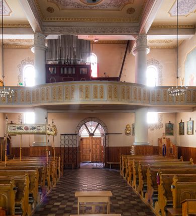 Zdjęcie nr 31: Kościół murowany z cegły na niskiej, kamiennej podmurówce, orientowany, jednonawowy ze zredukowanym transeptem oraz nieco niższym, zamkniętym półkoliście prezbiterium. Do północno-wschodniego narożnika nawy (przy prezbiterium) przylega założona na rzucie prostokąta, oszkarpowana zakrystia dostępna półkolistym portalem od strony północnej. Do południowo-wschodniego narożnika nawy dostawiona kaplica Matki Boskiej na rzucie prostokąta zamknięta od wschodu niewielką absydą. Ramiona transeptu zredukowane do roli prostokątnych kaplic. Do południowo-zachodniego i północno-zachodniego narożnika nawy dobudowane nowsze kruchty boczne założone na rzucie prostokąta dostępne portalami o półkolistym wykroju. Kruchta zachodnia na rzucie prostokąta dostępna nowym, prostokątnym wejściem. W ścianach północnej i południowej widoczne, zamurowane, starsze otwory wejściowe (od południa w miejsce portalu okrągłe okno). Dach nad nawą dwuspadowy z trzecią połacią zakrywającą ścianę szczytową; w części wschodniej wieloboczna wieżyczka na sygnaturkę z glorietą zwieńczoną krzyżem. Kruchty oraz kaplice boczne kryte dachami trójpołaciowymi, prezbiterium jednopołaciowym; nad zakrystią dach mansardowy z prostokątnym oknem w lukarnie. Pokrycia dachowe wykonane są z blachy (pierwotnie była to czerwona dachówka). W nawie i prezbiterium strop o konstrukcji żelbetowej wsparty na dziewięciu masywnych kolumnach ustawionych na wysokich cokołach; kaplice boczne sklepione krzyżowo, w zakrystii założony betonowy strop. Chór muzyczny murowany, wsparty na pierwszej od zachodu parze kolumn dźwigających strop. Fasada jednokondygnacyjna, trójosiowa z umieszczoną w osi centralnej prostopadłościenną kruchtą mieszczącą prostokątny otwór wejściowy (nowy). Okna w kształcie stojącego prostokąta o smukłych proporcjach, zamknięte półkoliście. Okno środkowe, umieszczone nieco wyżej, niższe od pozostałych. W ścianach zachodnich krucht bocznych po jednym niewielkim oknie o wykroju półkolistym. Trójkątna ściana szczytowa zasłonięta blaszanym dachem o przełamanej w dolnej części połaci, zwieńczona niewielkim, metalowym krzyżem. Elewacje boczne jednokondygnacyjne, o nieregularnym przebiegu osi. W elewacji południowej w pierwszej osi ceglany portal z nadświetlem o wykroju półkolistym, w drugiej okrągłe okno doświetlające kaplicę boczną, w kolejnych: półkolisty ceglany portal do zakrystii oraz okno o półkolistym wykroju z motywem biforium. W elewacji północnej w osi pierwszej i drugiej niewielkie półkoliście wykrojone okna, w osi trzeciej okrągłe okno doświetlające kaplicę, w osi czwartej natomiast ceglany portal  z nadświetlem o wykroju półkolistym. W prezbiterium cztery okna o wykroju półkolistym. W trzeciej osi, pomiędzy oknami, ujęta wielobocznymi filarami dźwigającymi, wydatny, profilowany gzyms tynkowana na biało nisza z figurą Matki Boskiej Fatimskiej umieszczonej pod baldachimem. Górną część murów nawy, prezbiterium, zakrystii, kaplic oraz obu krucht bocznych obiega profilowany gzyms okapowy. 