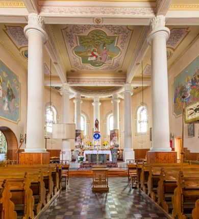 Zdjęcie nr 16: Kościół murowany z cegły na niskiej, kamiennej podmurówce, orientowany, jednonawowy ze zredukowanym transeptem oraz nieco niższym, zamkniętym półkoliście prezbiterium. Do północno-wschodniego narożnika nawy (przy prezbiterium) przylega założona na rzucie prostokąta, oszkarpowana zakrystia dostępna półkolistym portalem od strony północnej. Do południowo-wschodniego narożnika nawy dostawiona kaplica Matki Boskiej na rzucie prostokąta zamknięta od wschodu niewielką absydą. Ramiona transeptu zredukowane do roli prostokątnych kaplic. Do południowo-zachodniego i północno-zachodniego narożnika nawy dobudowane nowsze kruchty boczne założone na rzucie prostokąta dostępne portalami o półkolistym wykroju. Kruchta zachodnia na rzucie prostokąta dostępna nowym, prostokątnym wejściem. W ścianach północnej i południowej widoczne, zamurowane, starsze otwory wejściowe (od południa w miejsce portalu okrągłe okno). Dach nad nawą dwuspadowy z trzecią połacią zakrywającą ścianę szczytową; w części wschodniej wieloboczna wieżyczka na sygnaturkę z glorietą zwieńczoną krzyżem. Kruchty oraz kaplice boczne kryte dachami trójpołaciowymi, prezbiterium jednopołaciowym; nad zakrystią dach mansardowy z prostokątnym oknem w lukarnie. Pokrycia dachowe wykonane są z blachy (pierwotnie była to czerwona dachówka). W nawie i prezbiterium strop o konstrukcji żelbetowej wsparty na dziewięciu masywnych kolumnach ustawionych na wysokich cokołach; kaplice boczne sklepione krzyżowo, w zakrystii założony betonowy strop. Chór muzyczny murowany, wsparty na pierwszej od zachodu parze kolumn dźwigających strop. Fasada jednokondygnacyjna, trójosiowa z umieszczoną w osi centralnej prostopadłościenną kruchtą mieszczącą prostokątny otwór wejściowy (nowy). Okna w kształcie stojącego prostokąta o smukłych proporcjach, zamknięte półkoliście. Okno środkowe, umieszczone nieco wyżej, niższe od pozostałych. W ścianach zachodnich krucht bocznych po jednym niewielkim oknie o wykroju półkolistym. Trójkątna ściana szczytowa zasłonięta blaszanym dachem o przełamanej w dolnej części połaci, zwieńczona niewielkim, metalowym krzyżem. Elewacje boczne jednokondygnacyjne, o nieregularnym przebiegu osi. W elewacji południowej w pierwszej osi ceglany portal z nadświetlem o wykroju półkolistym, w drugiej okrągłe okno doświetlające kaplicę boczną, w kolejnych: półkolisty ceglany portal do zakrystii oraz okno o półkolistym wykroju z motywem biforium. W elewacji północnej w osi pierwszej i drugiej niewielkie półkoliście wykrojone okna, w osi trzeciej okrągłe okno doświetlające kaplicę, w osi czwartej natomiast ceglany portal  z nadświetlem o wykroju półkolistym. W prezbiterium cztery okna o wykroju półkolistym. W trzeciej osi, pomiędzy oknami, ujęta wielobocznymi filarami dźwigającymi, wydatny, profilowany gzyms tynkowana na biało nisza z figurą Matki Boskiej Fatimskiej umieszczonej pod baldachimem. Górną część murów nawy, prezbiterium, zakrystii, kaplic oraz obu krucht bocznych obiega profilowany gzyms okapowy. 