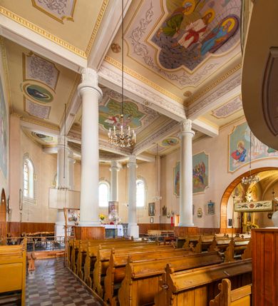 Zdjęcie nr 29: Kościół murowany z cegły na niskiej, kamiennej podmurówce, orientowany, jednonawowy ze zredukowanym transeptem oraz nieco niższym, zamkniętym półkoliście prezbiterium. Do północno-wschodniego narożnika nawy (przy prezbiterium) przylega założona na rzucie prostokąta, oszkarpowana zakrystia dostępna półkolistym portalem od strony północnej. Do południowo-wschodniego narożnika nawy dostawiona kaplica Matki Boskiej na rzucie prostokąta zamknięta od wschodu niewielką absydą. Ramiona transeptu zredukowane do roli prostokątnych kaplic. Do południowo-zachodniego i północno-zachodniego narożnika nawy dobudowane nowsze kruchty boczne założone na rzucie prostokąta dostępne portalami o półkolistym wykroju. Kruchta zachodnia na rzucie prostokąta dostępna nowym, prostokątnym wejściem. W ścianach północnej i południowej widoczne, zamurowane, starsze otwory wejściowe (od południa w miejsce portalu okrągłe okno). Dach nad nawą dwuspadowy z trzecią połacią zakrywającą ścianę szczytową; w części wschodniej wieloboczna wieżyczka na sygnaturkę z glorietą zwieńczoną krzyżem. Kruchty oraz kaplice boczne kryte dachami trójpołaciowymi, prezbiterium jednopołaciowym; nad zakrystią dach mansardowy z prostokątnym oknem w lukarnie. Pokrycia dachowe wykonane są z blachy (pierwotnie była to czerwona dachówka). W nawie i prezbiterium strop o konstrukcji żelbetowej wsparty na dziewięciu masywnych kolumnach ustawionych na wysokich cokołach; kaplice boczne sklepione krzyżowo, w zakrystii założony betonowy strop. Chór muzyczny murowany, wsparty na pierwszej od zachodu parze kolumn dźwigających strop. Fasada jednokondygnacyjna, trójosiowa z umieszczoną w osi centralnej prostopadłościenną kruchtą mieszczącą prostokątny otwór wejściowy (nowy). Okna w kształcie stojącego prostokąta o smukłych proporcjach, zamknięte półkoliście. Okno środkowe, umieszczone nieco wyżej, niższe od pozostałych. W ścianach zachodnich krucht bocznych po jednym niewielkim oknie o wykroju półkolistym. Trójkątna ściana szczytowa zasłonięta blaszanym dachem o przełamanej w dolnej części połaci, zwieńczona niewielkim, metalowym krzyżem. Elewacje boczne jednokondygnacyjne, o nieregularnym przebiegu osi. W elewacji południowej w pierwszej osi ceglany portal z nadświetlem o wykroju półkolistym, w drugiej okrągłe okno doświetlające kaplicę boczną, w kolejnych: półkolisty ceglany portal do zakrystii oraz okno o półkolistym wykroju z motywem biforium. W elewacji północnej w osi pierwszej i drugiej niewielkie półkoliście wykrojone okna, w osi trzeciej okrągłe okno doświetlające kaplicę, w osi czwartej natomiast ceglany portal  z nadświetlem o wykroju półkolistym. W prezbiterium cztery okna o wykroju półkolistym. W trzeciej osi, pomiędzy oknami, ujęta wielobocznymi filarami dźwigającymi, wydatny, profilowany gzyms tynkowana na biało nisza z figurą Matki Boskiej Fatimskiej umieszczonej pod baldachimem. Górną część murów nawy, prezbiterium, zakrystii, kaplic oraz obu krucht bocznych obiega profilowany gzyms okapowy. 