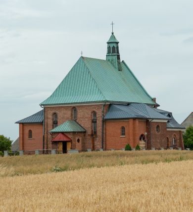 Zdjęcie nr 1: Kościół murowany z cegły na niskiej, kamiennej podmurówce, orientowany, jednonawowy ze zredukowanym transeptem oraz nieco niższym, zamkniętym półkoliście prezbiterium. Do północno-wschodniego narożnika nawy (przy prezbiterium) przylega założona na rzucie prostokąta, oszkarpowana zakrystia dostępna półkolistym portalem od strony północnej. Do południowo-wschodniego narożnika nawy dostawiona kaplica Matki Boskiej na rzucie prostokąta zamknięta od wschodu niewielką absydą. Ramiona transeptu zredukowane do roli prostokątnych kaplic. Do południowo-zachodniego i północno-zachodniego narożnika nawy dobudowane nowsze kruchty boczne założone na rzucie prostokąta dostępne portalami o półkolistym wykroju. Kruchta zachodnia na rzucie prostokąta dostępna nowym, prostokątnym wejściem. W ścianach północnej i południowej widoczne, zamurowane, starsze otwory wejściowe (od południa w miejsce portalu okrągłe okno). Dach nad nawą dwuspadowy z trzecią połacią zakrywającą ścianę szczytową; w części wschodniej wieloboczna wieżyczka na sygnaturkę z glorietą zwieńczoną krzyżem. Kruchty oraz kaplice boczne kryte dachami trójpołaciowymi, prezbiterium jednopołaciowym; nad zakrystią dach mansardowy z prostokątnym oknem w lukarnie. Pokrycia dachowe wykonane są z blachy (pierwotnie była to czerwona dachówka). W nawie i prezbiterium strop o konstrukcji żelbetowej wsparty na dziewięciu masywnych kolumnach ustawionych na wysokich cokołach; kaplice boczne sklepione krzyżowo, w zakrystii założony betonowy strop. Chór muzyczny murowany, wsparty na pierwszej od zachodu parze kolumn dźwigających strop. Fasada jednokondygnacyjna, trójosiowa z umieszczoną w osi centralnej prostopadłościenną kruchtą mieszczącą prostokątny otwór wejściowy (nowy). Okna w kształcie stojącego prostokąta o smukłych proporcjach, zamknięte półkoliście. Okno środkowe, umieszczone nieco wyżej, niższe od pozostałych. W ścianach zachodnich krucht bocznych po jednym niewielkim oknie o wykroju półkolistym. Trójkątna ściana szczytowa zasłonięta blaszanym dachem o przełamanej w dolnej części połaci, zwieńczona niewielkim, metalowym krzyżem. Elewacje boczne jednokondygnacyjne, o nieregularnym przebiegu osi. W elewacji południowej w pierwszej osi ceglany portal z nadświetlem o wykroju półkolistym, w drugiej okrągłe okno doświetlające kaplicę boczną, w kolejnych: półkolisty ceglany portal do zakrystii oraz okno o półkolistym wykroju z motywem biforium. W elewacji północnej w osi pierwszej i drugiej niewielkie półkoliście wykrojone okna, w osi trzeciej okrągłe okno doświetlające kaplicę, w osi czwartej natomiast ceglany portal  z nadświetlem o wykroju półkolistym. W prezbiterium cztery okna o wykroju półkolistym. W trzeciej osi, pomiędzy oknami, ujęta wielobocznymi filarami dźwigającymi, wydatny, profilowany gzyms tynkowana na biało nisza z figurą Matki Boskiej Fatimskiej umieszczonej pod baldachimem. Górną część murów nawy, prezbiterium, zakrystii, kaplic oraz obu krucht bocznych obiega profilowany gzyms okapowy. 