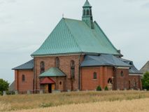 Zdjęcie nr 1: Kościół murowany z cegły na niskiej, kamiennej podmurówce, orientowany, jednonawowy ze zredukowanym transeptem oraz nieco niższym, zamkniętym półkoliście prezbiterium. Do północno-wschodniego narożnika nawy (przy prezbiterium) przylega założona na rzucie prostokąta, oszkarpowana zakrystia dostępna półkolistym portalem od strony północnej. Do południowo-wschodniego narożnika nawy dostawiona kaplica Matki Boskiej na rzucie prostokąta zamknięta od wschodu niewielką absydą. Ramiona transeptu zredukowane do roli prostokątnych kaplic. Do południowo-zachodniego i północno-zachodniego narożnika nawy dobudowane nowsze kruchty boczne założone na rzucie prostokąta dostępne portalami o półkolistym wykroju. Kruchta zachodnia na rzucie prostokąta dostępna nowym, prostokątnym wejściem. W ścianach północnej i południowej widoczne, zamurowane, starsze otwory wejściowe (od południa w miejsce portalu okrągłe okno). Dach nad nawą dwuspadowy z trzecią połacią zakrywającą ścianę szczytową; w części wschodniej wieloboczna wieżyczka na sygnaturkę z glorietą zwieńczoną krzyżem. Kruchty oraz kaplice boczne kryte dachami trójpołaciowymi, prezbiterium jednopołaciowym; nad zakrystią dach mansardowy z prostokątnym oknem w lukarnie. Pokrycia dachowe wykonane są z blachy (pierwotnie była to czerwona dachówka). W nawie i prezbiterium strop o konstrukcji żelbetowej wsparty na dziewięciu masywnych kolumnach ustawionych na wysokich cokołach; kaplice boczne sklepione krzyżowo, w zakrystii założony betonowy strop. Chór muzyczny murowany, wsparty na pierwszej od zachodu parze kolumn dźwigających strop. Fasada jednokondygnacyjna, trójosiowa z umieszczoną w osi centralnej prostopadłościenną kruchtą mieszczącą prostokątny otwór wejściowy (nowy). Okna w kształcie stojącego prostokąta o smukłych proporcjach, zamknięte półkoliście. Okno środkowe, umieszczone nieco wyżej, niższe od pozostałych. W ścianach zachodnich krucht bocznych po jednym niewielkim oknie o wykroju półkolistym. Trójkątna ściana szczytowa zasłonięta blaszanym dachem o przełamanej w dolnej części połaci, zwieńczona niewielkim, metalowym krzyżem. Elewacje boczne jednokondygnacyjne, o nieregularnym przebiegu osi. W elewacji południowej w pierwszej osi ceglany portal z nadświetlem o wykroju półkolistym, w drugiej okrągłe okno doświetlające kaplicę boczną, w kolejnych: półkolisty ceglany portal do zakrystii oraz okno o półkolistym wykroju z motywem biforium. W elewacji północnej w osi pierwszej i drugiej niewielkie półkoliście wykrojone okna, w osi trzeciej okrągłe okno doświetlające kaplicę, w osi czwartej natomiast ceglany portal  z nadświetlem o wykroju półkolistym. W prezbiterium cztery okna o wykroju półkolistym. W trzeciej osi, pomiędzy oknami, ujęta wielobocznymi filarami dźwigającymi, wydatny, profilowany gzyms tynkowana na biało nisza z figurą Matki Boskiej Fatimskiej umieszczonej pod baldachimem. Górną część murów nawy, prezbiterium, zakrystii, kaplic oraz obu krucht bocznych obiega profilowany gzyms okapowy. 