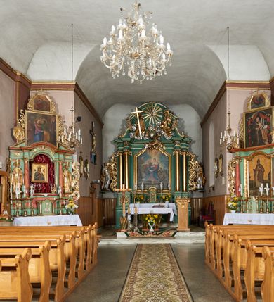 Zdjęcie nr 4: Kościół orientowany, murowany z kamienia i cegły, na planie prostokąta z szerszą nawą i węższym prezbiterium o zamknięciu wielobocznym, dobudowaną zakrystią, kruchtą od frontu i przedsionkiem od południa.  Od zachodu chór muzyczny z organami wsparty na dwóch kolumnach. Na ścianach iluzjonistyczne płyciny z fragmentami wici akantowej, glify we wnękach okiennych, na gzymsie ornament kostkowy, na stropie delikatna polichromia geometryczna z fragmentami wici akantowej. 
Nawa i prezbiterium przykryte stropem z głęboką fasetą imitującą sklepienie zwierciadlane, z oddzielającym je od partii ścian gzymsem. 
Otwory okienne w kształcie stojących prostokątów zakończonych półkoliście, różnej wielkości. Jedno okno w prezbiterium, po dwa z każdej strony nawy, dwa w kruchcie, dwa w fasadzie, a powyżej nich niewielki okulus. 
Główne wejście do kościoła od zachodu, przez kruchtę, kolejne od południa, przez przybudówkę, następne do zakrystii i do kotłowni.
Fasada została zakomponowana z dwóch części. Ściana kościoła jest zwieńczona trójkątnym szczytem ujętym niewysokimi murkami i zakończonym półokrągło, a przed jej lico wychodzi prostopadłościenna kruchta z małym, trójkątnym szczytem opracowanym podobnie jak szczyt fasady. 
Kościół ustawiony na cokole z kamienną okładziną. Elewacje zewnętrzne są gładkie, z podziałami lizenowo-ramowymi:  naroża podkreślone lizenami, kondygnacja oddzielona od partii dachu gzymsem podokapowym. 
Dachy dwuspadowe, kryte dachówką, na kalenicy nawy sześcioboczna wieżyczka na sygnaturkę z hełmem cebulastym krytym blachą. 
