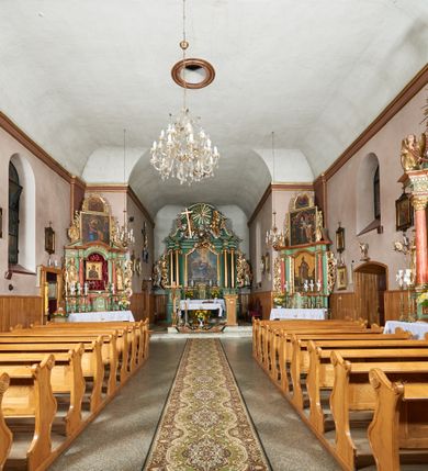 Zdjęcie nr 8: Kościół orientowany, murowany z kamienia i cegły, na planie prostokąta z szerszą nawą i węższym prezbiterium o zamknięciu wielobocznym, dobudowaną zakrystią, kruchtą od frontu i przedsionkiem od południa.  Od zachodu chór muzyczny z organami wsparty na dwóch kolumnach. Na ścianach iluzjonistyczne płyciny z fragmentami wici akantowej, glify we wnękach okiennych, na gzymsie ornament kostkowy, na stropie delikatna polichromia geometryczna z fragmentami wici akantowej. 
Nawa i prezbiterium przykryte stropem z głęboką fasetą imitującą sklepienie zwierciadlane, z oddzielającym je od partii ścian gzymsem. 
Otwory okienne w kształcie stojących prostokątów zakończonych półkoliście, różnej wielkości. Jedno okno w prezbiterium, po dwa z każdej strony nawy, dwa w kruchcie, dwa w fasadzie, a powyżej nich niewielki okulus. 
Główne wejście do kościoła od zachodu, przez kruchtę, kolejne od południa, przez przybudówkę, następne do zakrystii i do kotłowni.
Fasada została zakomponowana z dwóch części. Ściana kościoła jest zwieńczona trójkątnym szczytem ujętym niewysokimi murkami i zakończonym półokrągło, a przed jej lico wychodzi prostopadłościenna kruchta z małym, trójkątnym szczytem opracowanym podobnie jak szczyt fasady. 
Kościół ustawiony na cokole z kamienną okładziną. Elewacje zewnętrzne są gładkie, z podziałami lizenowo-ramowymi:  naroża podkreślone lizenami, kondygnacja oddzielona od partii dachu gzymsem podokapowym. 
Dachy dwuspadowe, kryte dachówką, na kalenicy nawy sześcioboczna wieżyczka na sygnaturkę z hełmem cebulastym krytym blachą. 