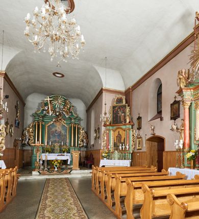 Zdjęcie nr 12: Kościół orientowany, murowany z kamienia i cegły, na planie prostokąta z szerszą nawą i węższym prezbiterium o zamknięciu wielobocznym, dobudowaną zakrystią, kruchtą od frontu i przedsionkiem od południa.  Od zachodu chór muzyczny z organami wsparty na dwóch kolumnach. Na ścianach iluzjonistyczne płyciny z fragmentami wici akantowej, glify we wnękach okiennych, na gzymsie ornament kostkowy, na stropie delikatna polichromia geometryczna z fragmentami wici akantowej. 
Nawa i prezbiterium przykryte stropem z głęboką fasetą imitującą sklepienie zwierciadlane, z oddzielającym je od partii ścian gzymsem. 
Otwory okienne w kształcie stojących prostokątów zakończonych półkoliście, różnej wielkości. Jedno okno w prezbiterium, po dwa z każdej strony nawy, dwa w kruchcie, dwa w fasadzie, a powyżej nich niewielki okulus. 
Główne wejście do kościoła od zachodu, przez kruchtę, kolejne od południa, przez przybudówkę, następne do zakrystii i do kotłowni.
Fasada została zakomponowana z dwóch części. Ściana kościoła jest zwieńczona trójkątnym szczytem ujętym niewysokimi murkami i zakończonym półokrągło, a przed jej lico wychodzi prostopadłościenna kruchta z małym, trójkątnym szczytem opracowanym podobnie jak szczyt fasady. 
Kościół ustawiony na cokole z kamienną okładziną. Elewacje zewnętrzne są gładkie, z podziałami lizenowo-ramowymi:  naroża podkreślone lizenami, kondygnacja oddzielona od partii dachu gzymsem podokapowym. 
Dachy dwuspadowe, kryte dachówką, na kalenicy nawy sześcioboczna wieżyczka na sygnaturkę z hełmem cebulastym krytym blachą. 