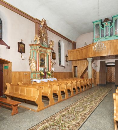 Zdjęcie nr 10: Kościół orientowany, murowany z kamienia i cegły, na planie prostokąta z szerszą nawą i węższym prezbiterium o zamknięciu wielobocznym, dobudowaną zakrystią, kruchtą od frontu i przedsionkiem od południa.  Od zachodu chór muzyczny z organami wsparty na dwóch kolumnach. Na ścianach iluzjonistyczne płyciny z fragmentami wici akantowej, glify we wnękach okiennych, na gzymsie ornament kostkowy, na stropie delikatna polichromia geometryczna z fragmentami wici akantowej. 
Nawa i prezbiterium przykryte stropem z głęboką fasetą imitującą sklepienie zwierciadlane, z oddzielającym je od partii ścian gzymsem. 
Otwory okienne w kształcie stojących prostokątów zakończonych półkoliście, różnej wielkości. Jedno okno w prezbiterium, po dwa z każdej strony nawy, dwa w kruchcie, dwa w fasadzie, a powyżej nich niewielki okulus. 
Główne wejście do kościoła od zachodu, przez kruchtę, kolejne od południa, przez przybudówkę, następne do zakrystii i do kotłowni.
Fasada została zakomponowana z dwóch części. Ściana kościoła jest zwieńczona trójkątnym szczytem ujętym niewysokimi murkami i zakończonym półokrągło, a przed jej lico wychodzi prostopadłościenna kruchta z małym, trójkątnym szczytem opracowanym podobnie jak szczyt fasady. 
Kościół ustawiony na cokole z kamienną okładziną. Elewacje zewnętrzne są gładkie, z podziałami lizenowo-ramowymi:  naroża podkreślone lizenami, kondygnacja oddzielona od partii dachu gzymsem podokapowym. 
Dachy dwuspadowe, kryte dachówką, na kalenicy nawy sześcioboczna wieżyczka na sygnaturkę z hełmem cebulastym krytym blachą. 
