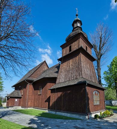 Zdjęcie nr 1: Kościół orientowany, drewniany, na podmurówce z kamienia łupanego, konstrukcji zrębowej, jednonawowy, szalowany, z wieżą konstrukcji słupowej usytuowaną od strony prezbiterium, z zakrystią w przyziemiu. Nawa prostokątna, szersza od prezbiterium, z kruchtami od zachodu, południa i północy. Prezbiterium zamknięte trójbocznie. Wieża od wschodu, na planie kwadratu, o konstrukcji ze słupów pochyłych, na zewnątrz trzy kondygnacje przedzielone obiegającymi daszkami. Dolna i górna izbica o ścianach pionowych, środkowa o ścianach pochyłych; wieża zwieńczona hełmem baniastym z latarnią. Kościół przykrywa dach siodłowy, na kruchtach trójspadowy, kryty cementówką. Pod wydatnymi okapami dachów biegnie gzyms o profilu ćwierćkoliście wklęsłym z wałkiem. Więźba dachowa nad prezbiterium jest krokwiowa, a nad nawą płatwiowa. Wewnątrz znajdują się stropy z fasetami, pod którymi umieszczony jest profilowany gzyms. Arkada tęczowa o łuku spłaszczonym. Chór muzyczny wsparty jest na dwóch filarach z wybrzuszoną balustradą. Wnętrze polichromowane, ściany w kruchtach oszalowane. Do kościoła prowadzą cztery wejścia: główne od zachodu, dwa boczne od południa i północy oraz przez zakrystię od wieży, od strony północno-zachodniej. W prezbiterium znajdują się dwa okna: po stronie południowej i północnej; a w nawie dwa po stronie południowej i północnej, natomiast w wieży cztery okna prostokątne, w latarni osiem okien zamkniętych dwoma nałęczami. Kościół otoczony jest murkiem ze stacjami drogi krzyżowej i dwiema bramkami z lat 1863 i 1864.