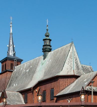 Zdjęcie nr 1: Kościół Przemienienia Pańskiego w Radoczy usytuowany jest w centrum wsi na zachód od głównej drogi prowadzącej z Wadowic do Zatora. Teren przykościelny jest usytuowany na niewielkim wzniesieniu, otoczony drewnianym płotem. Główne wejście na plac przykościelny prowadzi przez bramę od strony zachodniej.

Kościół jest orientowany, drewniany o konstrukcji zrębowej z wieżą na słup, jednonawowy z krótszym prezbiterium zamkniętym trójbocznie. Przy prezbiterium od wschodu nowsza zakrystia murowana, od północy kaplica i składzik, przy nawie od południa kruchta. Wnętrze nakryte pułapem, w nawie z zaskrzynieniami. Ściana arkady tęczowej o wykroju prostokątnym ze ściętymi narożami. Do kościoła prowadzi główne wejście w wieży od strony północnej. Wnętrze świątyni oświetlają prostokątne okna od strony południowej. Dach o jednej kalenicy, kryty blachą, na środku drewniana sygnaturka, nakryta kopułką z latarnią.  Od zachodu wieża w dolnej kondygnacji na planie prostokąta, ujęta po bokach daszkami; druga kondygnacja o ścianach pochyłych, pokryta gontem; trzecia kondygnacja prześwietlona prostokątnymi otworami okiennymi; wieża zakończona iglicą. Ściany na zewnątrz pokryte szalunkiem pionowym.
