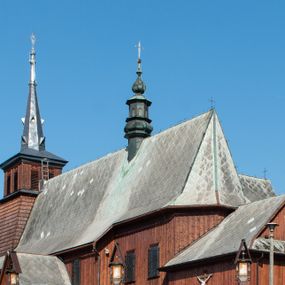 Zdjęcie nr 1: Kościół Przemienienia Pańskiego w Radoczy usytuowany jest w centrum wsi na zachód od głównej drogi prowadzącej z Wadowic do Zatora. Teren przykościelny jest usytuowany na niewielkim wzniesieniu, otoczony drewnianym płotem. Główne wejście na plac przykościelny prowadzi przez bramę od strony zachodniej.
Kościół jest orientowany, drewniany o konstrukcji zrębowej z wieżą na słup, jednonawowy z krótszym prezbiterium zamkniętym trójbocznie. Przy prezbiterium od wschodu nowsza zakrystia murowana, od północy kaplica i składzik, przy nawie od południa kruchta. Wnętrze nakryte pułapem, w nawie z zaskrzynieniami. Ściana arkady tęczowej o wykroju prostokątnym ze ściętymi narożami. Do kościoła prowadzi główne wejście w wieży od strony północnej. Wnętrze świątyni oświetlają prostokątne okna od strony południowej. Dach o jednej kalenicy, kryty blachą, na środku drewniana sygnaturka, nakryta kopułką z latarnią.  Od zachodu wieża w dolnej kondygnacji na planie prostokąta, ujęta po bokach daszkami; druga kondygnacja o ścianach pochyłych, pokryta gontem; trzecia kondygnacja prześwietlona prostokątnymi otworami okiennymi; wieża zakończona iglicą. Ściany na zewnątrz pokryte szalunkiem pionowym.