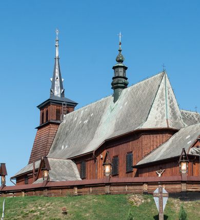 Zdjęcie nr 2: Kościół Przemienienia Pańskiego w Radoczy usytuowany jest w centrum wsi na zachód od głównej drogi prowadzącej z Wadowic do Zatora. Teren przykościelny jest usytuowany na niewielkim wzniesieniu, otoczony drewnianym płotem. Główne wejście na plac przykościelny prowadzi przez bramę od strony zachodniej.

Kościół jest orientowany, drewniany o konstrukcji zrębowej z wieżą na słup, jednonawowy z krótszym prezbiterium zamkniętym trójbocznie. Przy prezbiterium od wschodu nowsza zakrystia murowana, od północy kaplica i składzik, przy nawie od południa kruchta. Wnętrze nakryte pułapem, w nawie z zaskrzynieniami. Ściana arkady tęczowej o wykroju prostokątnym ze ściętymi narożami. Do kościoła prowadzi główne wejście w wieży od strony północnej. Wnętrze świątyni oświetlają prostokątne okna od strony południowej. Dach o jednej kalenicy, kryty blachą, na środku drewniana sygnaturka, nakryta kopułką z latarnią.  Od zachodu wieża w dolnej kondygnacji na planie prostokąta, ujęta po bokach daszkami; druga kondygnacja o ścianach pochyłych, pokryta gontem; trzecia kondygnacja prześwietlona prostokątnymi otworami okiennymi; wieża zakończona iglicą. Ściany na zewnątrz pokryte szalunkiem pionowym.
