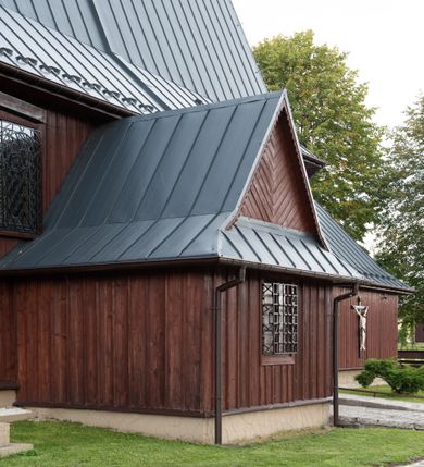 Zdjęcie nr 31: Kościół Przemienienia Pańskiego w Radoczy usytuowany jest w centrum wsi na zachód od głównej drogi prowadzącej z Wadowic do Zatora. Teren przykościelny jest usytuowany na niewielkim wzniesieniu, otoczony drewnianym płotem. Główne wejście na plac przykościelny prowadzi przez bramę od strony zachodniej.

Kościół jest orientowany, drewniany o konstrukcji zrębowej z wieżą na słup, jednonawowy z krótszym prezbiterium zamkniętym trójbocznie. Przy prezbiterium od wschodu nowsza zakrystia murowana, od północy kaplica i składzik, przy nawie od południa kruchta. Wnętrze nakryte pułapem, w nawie z zaskrzynieniami. Ściana arkady tęczowej o wykroju prostokątnym ze ściętymi narożami. Do kościoła prowadzi główne wejście w wieży od strony północnej. Wnętrze świątyni oświetlają prostokątne okna od strony południowej. Dach o jednej kalenicy, kryty blachą, na środku drewniana sygnaturka, nakryta kopułką z latarnią.  Od zachodu wieża w dolnej kondygnacji na planie prostokąta, ujęta po bokach daszkami; druga kondygnacja o ścianach pochyłych, pokryta gontem; trzecia kondygnacja prześwietlona prostokątnymi otworami okiennymi; wieża zakończona iglicą. Ściany na zewnątrz pokryte szalunkiem pionowym.
