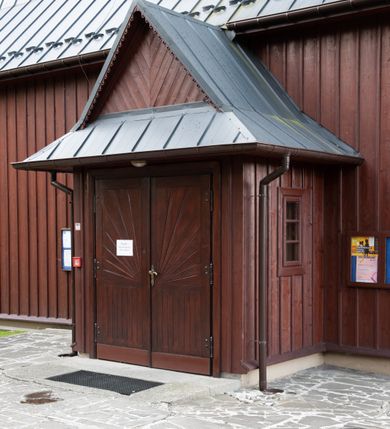 Zdjęcie nr 32: Kościół Przemienienia Pańskiego w Radoczy usytuowany jest w centrum wsi na zachód od głównej drogi prowadzącej z Wadowic do Zatora. Teren przykościelny jest usytuowany na niewielkim wzniesieniu, otoczony drewnianym płotem. Główne wejście na plac przykościelny prowadzi przez bramę od strony zachodniej.

Kościół jest orientowany, drewniany o konstrukcji zrębowej z wieżą na słup, jednonawowy z krótszym prezbiterium zamkniętym trójbocznie. Przy prezbiterium od wschodu nowsza zakrystia murowana, od północy kaplica i składzik, przy nawie od południa kruchta. Wnętrze nakryte pułapem, w nawie z zaskrzynieniami. Ściana arkady tęczowej o wykroju prostokątnym ze ściętymi narożami. Do kościoła prowadzi główne wejście w wieży od strony północnej. Wnętrze świątyni oświetlają prostokątne okna od strony południowej. Dach o jednej kalenicy, kryty blachą, na środku drewniana sygnaturka, nakryta kopułką z latarnią.  Od zachodu wieża w dolnej kondygnacji na planie prostokąta, ujęta po bokach daszkami; druga kondygnacja o ścianach pochyłych, pokryta gontem; trzecia kondygnacja prześwietlona prostokątnymi otworami okiennymi; wieża zakończona iglicą. Ściany na zewnątrz pokryte szalunkiem pionowym.
