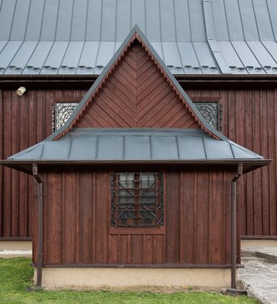 Zdjęcie nr 34: Kościół Przemienienia Pańskiego w Radoczy usytuowany jest w centrum wsi na zachód od głównej drogi prowadzącej z Wadowic do Zatora. Teren przykościelny jest usytuowany na niewielkim wzniesieniu, otoczony drewnianym płotem. Główne wejście na plac przykościelny prowadzi przez bramę od strony zachodniej.

Kościół jest orientowany, drewniany o konstrukcji zrębowej z wieżą na słup, jednonawowy z krótszym prezbiterium zamkniętym trójbocznie. Przy prezbiterium od wschodu nowsza zakrystia murowana, od północy kaplica i składzik, przy nawie od południa kruchta. Wnętrze nakryte pułapem, w nawie z zaskrzynieniami. Ściana arkady tęczowej o wykroju prostokątnym ze ściętymi narożami. Do kościoła prowadzi główne wejście w wieży od strony północnej. Wnętrze świątyni oświetlają prostokątne okna od strony południowej. Dach o jednej kalenicy, kryty blachą, na środku drewniana sygnaturka, nakryta kopułką z latarnią.  Od zachodu wieża w dolnej kondygnacji na planie prostokąta, ujęta po bokach daszkami; druga kondygnacja o ścianach pochyłych, pokryta gontem; trzecia kondygnacja prześwietlona prostokątnymi otworami okiennymi; wieża zakończona iglicą. Ściany na zewnątrz pokryte szalunkiem pionowym.
