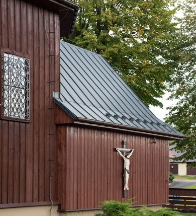 Zdjęcie nr 33: Kościół Przemienienia Pańskiego w Radoczy usytuowany jest w centrum wsi na zachód od głównej drogi prowadzącej z Wadowic do Zatora. Teren przykościelny jest usytuowany na niewielkim wzniesieniu, otoczony drewnianym płotem. Główne wejście na plac przykościelny prowadzi przez bramę od strony zachodniej.

Kościół jest orientowany, drewniany o konstrukcji zrębowej z wieżą na słup, jednonawowy z krótszym prezbiterium zamkniętym trójbocznie. Przy prezbiterium od wschodu nowsza zakrystia murowana, od północy kaplica i składzik, przy nawie od południa kruchta. Wnętrze nakryte pułapem, w nawie z zaskrzynieniami. Ściana arkady tęczowej o wykroju prostokątnym ze ściętymi narożami. Do kościoła prowadzi główne wejście w wieży od strony północnej. Wnętrze świątyni oświetlają prostokątne okna od strony południowej. Dach o jednej kalenicy, kryty blachą, na środku drewniana sygnaturka, nakryta kopułką z latarnią.  Od zachodu wieża w dolnej kondygnacji na planie prostokąta, ujęta po bokach daszkami; druga kondygnacja o ścianach pochyłych, pokryta gontem; trzecia kondygnacja prześwietlona prostokątnymi otworami okiennymi; wieża zakończona iglicą. Ściany na zewnątrz pokryte szalunkiem pionowym.
