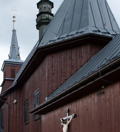 Zdjęcie nr 37: Kościół Przemienienia Pańskiego w Radoczy usytuowany jest w centrum wsi na zachód od głównej drogi prowadzącej z Wadowic do Zatora. Teren przykościelny jest usytuowany na niewielkim wzniesieniu, otoczony drewnianym płotem. Główne wejście na plac przykościelny prowadzi przez bramę od strony zachodniej.

Kościół jest orientowany, drewniany o konstrukcji zrębowej z wieżą na słup, jednonawowy z krótszym prezbiterium zamkniętym trójbocznie. Przy prezbiterium od wschodu nowsza zakrystia murowana, od północy kaplica i składzik, przy nawie od południa kruchta. Wnętrze nakryte pułapem, w nawie z zaskrzynieniami. Ściana arkady tęczowej o wykroju prostokątnym ze ściętymi narożami. Do kościoła prowadzi główne wejście w wieży od strony północnej. Wnętrze świątyni oświetlają prostokątne okna od strony południowej. Dach o jednej kalenicy, kryty blachą, na środku drewniana sygnaturka, nakryta kopułką z latarnią.  Od zachodu wieża w dolnej kondygnacji na planie prostokąta, ujęta po bokach daszkami; druga kondygnacja o ścianach pochyłych, pokryta gontem; trzecia kondygnacja prześwietlona prostokątnymi otworami okiennymi; wieża zakończona iglicą. Ściany na zewnątrz pokryte szalunkiem pionowym.
