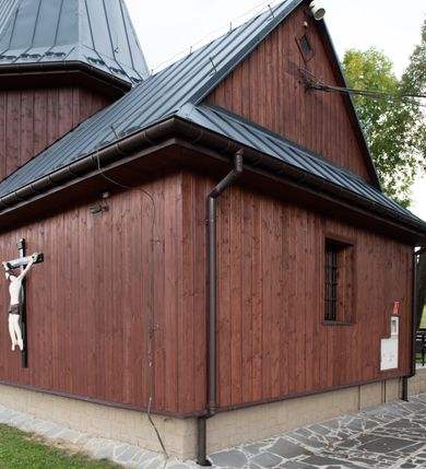 Zdjęcie nr 42: Kościół Przemienienia Pańskiego w Radoczy usytuowany jest w centrum wsi na zachód od głównej drogi prowadzącej z Wadowic do Zatora. Teren przykościelny jest usytuowany na niewielkim wzniesieniu, otoczony drewnianym płotem. Główne wejście na plac przykościelny prowadzi przez bramę od strony zachodniej.

Kościół jest orientowany, drewniany o konstrukcji zrębowej z wieżą na słup, jednonawowy z krótszym prezbiterium zamkniętym trójbocznie. Przy prezbiterium od wschodu nowsza zakrystia murowana, od północy kaplica i składzik, przy nawie od południa kruchta. Wnętrze nakryte pułapem, w nawie z zaskrzynieniami. Ściana arkady tęczowej o wykroju prostokątnym ze ściętymi narożami. Do kościoła prowadzi główne wejście w wieży od strony północnej. Wnętrze świątyni oświetlają prostokątne okna od strony południowej. Dach o jednej kalenicy, kryty blachą, na środku drewniana sygnaturka, nakryta kopułką z latarnią.  Od zachodu wieża w dolnej kondygnacji na planie prostokąta, ujęta po bokach daszkami; druga kondygnacja o ścianach pochyłych, pokryta gontem; trzecia kondygnacja prześwietlona prostokątnymi otworami okiennymi; wieża zakończona iglicą. Ściany na zewnątrz pokryte szalunkiem pionowym.
