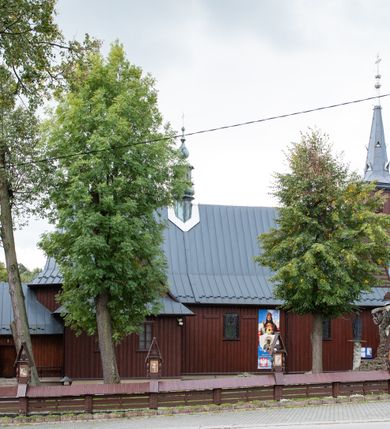 Zdjęcie nr 43: Kościół Przemienienia Pańskiego w Radoczy usytuowany jest w centrum wsi na zachód od głównej drogi prowadzącej z Wadowic do Zatora. Teren przykościelny jest usytuowany na niewielkim wzniesieniu, otoczony drewnianym płotem. Główne wejście na plac przykościelny prowadzi przez bramę od strony zachodniej.

Kościół jest orientowany, drewniany o konstrukcji zrębowej z wieżą na słup, jednonawowy z krótszym prezbiterium zamkniętym trójbocznie. Przy prezbiterium od wschodu nowsza zakrystia murowana, od północy kaplica i składzik, przy nawie od południa kruchta. Wnętrze nakryte pułapem, w nawie z zaskrzynieniami. Ściana arkady tęczowej o wykroju prostokątnym ze ściętymi narożami. Do kościoła prowadzi główne wejście w wieży od strony północnej. Wnętrze świątyni oświetlają prostokątne okna od strony południowej. Dach o jednej kalenicy, kryty blachą, na środku drewniana sygnaturka, nakryta kopułką z latarnią.  Od zachodu wieża w dolnej kondygnacji na planie prostokąta, ujęta po bokach daszkami; druga kondygnacja o ścianach pochyłych, pokryta gontem; trzecia kondygnacja prześwietlona prostokątnymi otworami okiennymi; wieża zakończona iglicą. Ściany na zewnątrz pokryte szalunkiem pionowym.
