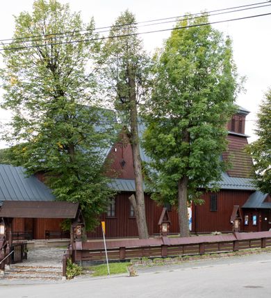 Zdjęcie nr 45: Kościół Przemienienia Pańskiego w Radoczy usytuowany jest w centrum wsi na zachód od głównej drogi prowadzącej z Wadowic do Zatora. Teren przykościelny jest usytuowany na niewielkim wzniesieniu, otoczony drewnianym płotem. Główne wejście na plac przykościelny prowadzi przez bramę od strony zachodniej.

Kościół jest orientowany, drewniany o konstrukcji zrębowej z wieżą na słup, jednonawowy z krótszym prezbiterium zamkniętym trójbocznie. Przy prezbiterium od wschodu nowsza zakrystia murowana, od północy kaplica i składzik, przy nawie od południa kruchta. Wnętrze nakryte pułapem, w nawie z zaskrzynieniami. Ściana arkady tęczowej o wykroju prostokątnym ze ściętymi narożami. Do kościoła prowadzi główne wejście w wieży od strony północnej. Wnętrze świątyni oświetlają prostokątne okna od strony południowej. Dach o jednej kalenicy, kryty blachą, na środku drewniana sygnaturka, nakryta kopułką z latarnią.  Od zachodu wieża w dolnej kondygnacji na planie prostokąta, ujęta po bokach daszkami; druga kondygnacja o ścianach pochyłych, pokryta gontem; trzecia kondygnacja prześwietlona prostokątnymi otworami okiennymi; wieża zakończona iglicą. Ściany na zewnątrz pokryte szalunkiem pionowym.
