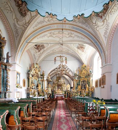 Zdjęcie nr 7: Kościół orientowany, murowany z kamienia, jednonawowy, z prostokątną, trójprzęsłową nawą oraz węższym dwuprzęsłowym prezbiterium zamkniętym prosto, z prostokątną zakrystią przy północnej ścianie. Od zachodu wieża na planie kwadratu, do północnej ściany nawy dobudowana kaplica na rzucie kwadratu o ściętych narożach, do południowej niewielka kruchta na planie kwadratu. Prezbiterium nakryte sklepieniem krzyżowo-żebrowym z dwoma zwornikami. 
Nawa sklepiona krzyżowo, przęsła wydzielone arkadami wspartymi na półfilarach. Otwór tęczowy w formie stojącego prostokąta zamkniętego łukiem półkolistym. W zachodniej części nawy parapet chóru muzycznego, z wybrzuszoną środkową częścią balustrady, wsparty na czterech kolumnach. 
Fasada wieżowa, z wejściem na osi. Wieża smukła, bez podziałów architektonicznych, zakończona profilowanym gzymsem, wyłamującym się na każdej ścianie na kształt łuku odcinkowego. W najwyższej partii ścian, z trzech stron, okna w formie stojącego prostokąta zamkniętego półkoliście. Wieża zwieńczona hełmem baniastym z latarnią, pokrytym gontem. 
Kościół opięty szkarpami dwuuskokowymi, nakrytymi daszkami gontowymi. W elewacji południowej pomiędzy szkarpami pięć wąskich okien w formie stojącego prostokąta zamkniętego łukiem półkolistym. Na wschodniej dobudowany ogrojec w formie masywnej arkady, zamkniętej dwuspadowym daszkiem z ołtarzem i krucyfiksem. Nawa i prezbiterium nakryte osobnymi dachami dwuspadowymi, gontowymi. Nad prezbiterium drewniana wieżyczka na sygnaturkę, z latarnią, zwieńczona hełmem baniastym. Kaplica przykryta dachem gontowych, trójspadowym, kruchta zaś pulpitowym. 
Kościół otoczony niskim murem kamiennym, nakrytym daszkiem gontowym. Od wschodu dwie bramy flankowane filarami z wazonami. 

