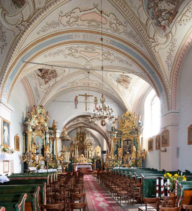 Zdjęcie nr 9: Kościół orientowany, murowany z kamienia, jednonawowy, z prostokątną, trójprzęsłową nawą oraz węższym dwuprzęsłowym prezbiterium zamkniętym prosto, z prostokątną zakrystią przy północnej ścianie. Od zachodu wieża na planie kwadratu, do północnej ściany nawy dobudowana kaplica na rzucie kwadratu o ściętych narożach, do południowej niewielka kruchta na planie kwadratu. Prezbiterium nakryte sklepieniem krzyżowo-żebrowym z dwoma zwornikami. 
Nawa sklepiona krzyżowo, przęsła wydzielone arkadami wspartymi na półfilarach. Otwór tęczowy w formie stojącego prostokąta zamkniętego łukiem półkolistym. W zachodniej części nawy parapet chóru muzycznego, z wybrzuszoną środkową częścią balustrady, wsparty na czterech kolumnach. 
Fasada wieżowa, z wejściem na osi. Wieża smukła, bez podziałów architektonicznych, zakończona profilowanym gzymsem, wyłamującym się na każdej ścianie na kształt łuku odcinkowego. W najwyższej partii ścian, z trzech stron, okna w formie stojącego prostokąta zamkniętego półkoliście. Wieża zwieńczona hełmem baniastym z latarnią, pokrytym gontem. 
Kościół opięty szkarpami dwuuskokowymi, nakrytymi daszkami gontowymi. W elewacji południowej pomiędzy szkarpami pięć wąskich okien w formie stojącego prostokąta zamkniętego łukiem półkolistym. Na wschodniej dobudowany ogrojec w formie masywnej arkady, zamkniętej dwuspadowym daszkiem z ołtarzem i krucyfiksem. Nawa i prezbiterium nakryte osobnymi dachami dwuspadowymi, gontowymi. Nad prezbiterium drewniana wieżyczka na sygnaturkę, z latarnią, zwieńczona hełmem baniastym. Kaplica przykryta dachem gontowych, trójspadowym, kruchta zaś pulpitowym. 
Kościół otoczony niskim murem kamiennym, nakrytym daszkiem gontowym. Od wschodu dwie bramy flankowane filarami z wazonami. 

