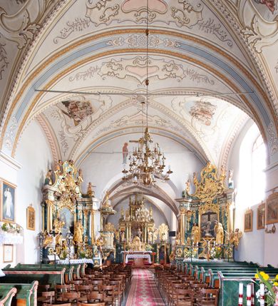 Zdjęcie nr 10: Kościół orientowany, murowany z kamienia, jednonawowy, z prostokątną, trójprzęsłową nawą oraz węższym dwuprzęsłowym prezbiterium zamkniętym prosto, z prostokątną zakrystią przy północnej ścianie. Od zachodu wieża na planie kwadratu, do północnej ściany nawy dobudowana kaplica na rzucie kwadratu o ściętych narożach, do południowej niewielka kruchta na planie kwadratu. Prezbiterium nakryte sklepieniem krzyżowo-żebrowym z dwoma zwornikami. 
Nawa sklepiona krzyżowo, przęsła wydzielone arkadami wspartymi na półfilarach. Otwór tęczowy w formie stojącego prostokąta zamkniętego łukiem półkolistym. W zachodniej części nawy parapet chóru muzycznego, z wybrzuszoną środkową częścią balustrady, wsparty na czterech kolumnach. 
Fasada wieżowa, z wejściem na osi. Wieża smukła, bez podziałów architektonicznych, zakończona profilowanym gzymsem, wyłamującym się na każdej ścianie na kształt łuku odcinkowego. W najwyższej partii ścian, z trzech stron, okna w formie stojącego prostokąta zamkniętego półkoliście. Wieża zwieńczona hełmem baniastym z latarnią, pokrytym gontem. 
Kościół opięty szkarpami dwuuskokowymi, nakrytymi daszkami gontowymi. W elewacji południowej pomiędzy szkarpami pięć wąskich okien w formie stojącego prostokąta zamkniętego łukiem półkolistym. Na wschodniej dobudowany ogrojec w formie masywnej arkady, zamkniętej dwuspadowym daszkiem z ołtarzem i krucyfiksem. Nawa i prezbiterium nakryte osobnymi dachami dwuspadowymi, gontowymi. Nad prezbiterium drewniana wieżyczka na sygnaturkę, z latarnią, zwieńczona hełmem baniastym. Kaplica przykryta dachem gontowych, trójspadowym, kruchta zaś pulpitowym. 
Kościół otoczony niskim murem kamiennym, nakrytym daszkiem gontowym. Od wschodu dwie bramy flankowane filarami z wazonami. 

