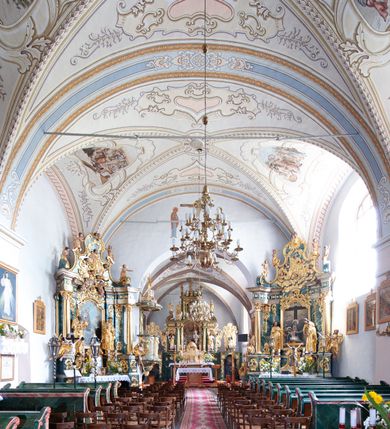 Zdjęcie nr 4: Kościół orientowany, murowany z kamienia, jednonawowy, z prostokątną, trójprzęsłową nawą oraz węższym dwuprzęsłowym prezbiterium zamkniętym prosto, z prostokątną zakrystią przy północnej ścianie. Od zachodu wieża na planie kwadratu, do północnej ściany nawy dobudowana kaplica na rzucie kwadratu o ściętych narożach, do południowej niewielka kruchta na planie kwadratu. Prezbiterium nakryte sklepieniem krzyżowo-żebrowym z dwoma zwornikami. 
Nawa sklepiona krzyżowo, przęsła wydzielone arkadami wspartymi na półfilarach. Otwór tęczowy w formie stojącego prostokąta zamkniętego łukiem półkolistym. W zachodniej części nawy parapet chóru muzycznego, z wybrzuszoną środkową częścią balustrady, wsparty na czterech kolumnach. 
Fasada wieżowa, z wejściem na osi. Wieża smukła, bez podziałów architektonicznych, zakończona profilowanym gzymsem, wyłamującym się na każdej ścianie na kształt łuku odcinkowego. W najwyższej partii ścian, z trzech stron, okna w formie stojącego prostokąta zamkniętego półkoliście. Wieża zwieńczona hełmem baniastym z latarnią, pokrytym gontem. 
Kościół opięty szkarpami dwuuskokowymi, nakrytymi daszkami gontowymi. W elewacji południowej pomiędzy szkarpami pięć wąskich okien w formie stojącego prostokąta zamkniętego łukiem półkolistym. Na wschodniej dobudowany ogrojec w formie masywnej arkady, zamkniętej dwuspadowym daszkiem z ołtarzem i krucyfiksem. Nawa i prezbiterium nakryte osobnymi dachami dwuspadowymi, gontowymi. Nad prezbiterium drewniana wieżyczka na sygnaturkę, z latarnią, zwieńczona hełmem baniastym. Kaplica przykryta dachem gontowych, trójspadowym, kruchta zaś pulpitowym. 
Kościół otoczony niskim murem kamiennym, nakrytym daszkiem gontowym. Od wschodu dwie bramy flankowane filarami z wazonami. 

