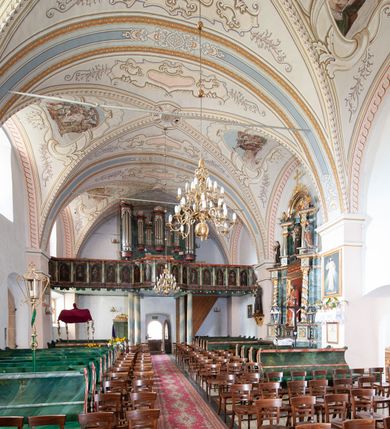 Zdjęcie nr 16: Kościół orientowany, murowany z kamienia, jednonawowy, z prostokątną, trójprzęsłową nawą oraz węższym dwuprzęsłowym prezbiterium zamkniętym prosto, z prostokątną zakrystią przy północnej ścianie. Od zachodu wieża na planie kwadratu, do północnej ściany nawy dobudowana kaplica na rzucie kwadratu o ściętych narożach, do południowej niewielka kruchta na planie kwadratu. Prezbiterium nakryte sklepieniem krzyżowo-żebrowym z dwoma zwornikami. 
Nawa sklepiona krzyżowo, przęsła wydzielone arkadami wspartymi na półfilarach. Otwór tęczowy w formie stojącego prostokąta zamkniętego łukiem półkolistym. W zachodniej części nawy parapet chóru muzycznego, z wybrzuszoną środkową częścią balustrady, wsparty na czterech kolumnach. 
Fasada wieżowa, z wejściem na osi. Wieża smukła, bez podziałów architektonicznych, zakończona profilowanym gzymsem, wyłamującym się na każdej ścianie na kształt łuku odcinkowego. W najwyższej partii ścian, z trzech stron, okna w formie stojącego prostokąta zamkniętego półkoliście. Wieża zwieńczona hełmem baniastym z latarnią, pokrytym gontem. 
Kościół opięty szkarpami dwuuskokowymi, nakrytymi daszkami gontowymi. W elewacji południowej pomiędzy szkarpami pięć wąskich okien w formie stojącego prostokąta zamkniętego łukiem półkolistym. Na wschodniej dobudowany ogrojec w formie masywnej arkady, zamkniętej dwuspadowym daszkiem z ołtarzem i krucyfiksem. Nawa i prezbiterium nakryte osobnymi dachami dwuspadowymi, gontowymi. Nad prezbiterium drewniana wieżyczka na sygnaturkę, z latarnią, zwieńczona hełmem baniastym. Kaplica przykryta dachem gontowych, trójspadowym, kruchta zaś pulpitowym. 
Kościół otoczony niskim murem kamiennym, nakrytym daszkiem gontowym. Od wschodu dwie bramy flankowane filarami z wazonami. 

