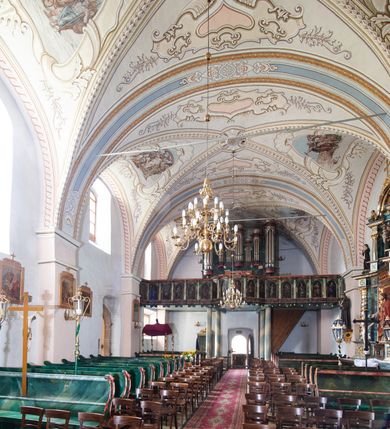 Zdjęcie nr 18: Kościół orientowany, murowany z kamienia, jednonawowy, z prostokątną, trójprzęsłową nawą oraz węższym dwuprzęsłowym prezbiterium zamkniętym prosto, z prostokątną zakrystią przy północnej ścianie. Od zachodu wieża na planie kwadratu, do północnej ściany nawy dobudowana kaplica na rzucie kwadratu o ściętych narożach, do południowej niewielka kruchta na planie kwadratu. Prezbiterium nakryte sklepieniem krzyżowo-żebrowym z dwoma zwornikami. 
Nawa sklepiona krzyżowo, przęsła wydzielone arkadami wspartymi na półfilarach. Otwór tęczowy w formie stojącego prostokąta zamkniętego łukiem półkolistym. W zachodniej części nawy parapet chóru muzycznego, z wybrzuszoną środkową częścią balustrady, wsparty na czterech kolumnach. 
Fasada wieżowa, z wejściem na osi. Wieża smukła, bez podziałów architektonicznych, zakończona profilowanym gzymsem, wyłamującym się na każdej ścianie na kształt łuku odcinkowego. W najwyższej partii ścian, z trzech stron, okna w formie stojącego prostokąta zamkniętego półkoliście. Wieża zwieńczona hełmem baniastym z latarnią, pokrytym gontem. 
Kościół opięty szkarpami dwuuskokowymi, nakrytymi daszkami gontowymi. W elewacji południowej pomiędzy szkarpami pięć wąskich okien w formie stojącego prostokąta zamkniętego łukiem półkolistym. Na wschodniej dobudowany ogrojec w formie masywnej arkady, zamkniętej dwuspadowym daszkiem z ołtarzem i krucyfiksem. Nawa i prezbiterium nakryte osobnymi dachami dwuspadowymi, gontowymi. Nad prezbiterium drewniana wieżyczka na sygnaturkę, z latarnią, zwieńczona hełmem baniastym. Kaplica przykryta dachem gontowych, trójspadowym, kruchta zaś pulpitowym. 
Kościół otoczony niskim murem kamiennym, nakrytym daszkiem gontowym. Od wschodu dwie bramy flankowane filarami z wazonami. 

