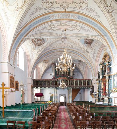 Zdjęcie nr 12: Kościół orientowany, murowany z kamienia, jednonawowy, z prostokątną, trójprzęsłową nawą oraz węższym dwuprzęsłowym prezbiterium zamkniętym prosto, z prostokątną zakrystią przy północnej ścianie. Od zachodu wieża na planie kwadratu, do północnej ściany nawy dobudowana kaplica na rzucie kwadratu o ściętych narożach, do południowej niewielka kruchta na planie kwadratu. Prezbiterium nakryte sklepieniem krzyżowo-żebrowym z dwoma zwornikami. 
Nawa sklepiona krzyżowo, przęsła wydzielone arkadami wspartymi na półfilarach. Otwór tęczowy w formie stojącego prostokąta zamkniętego łukiem półkolistym. W zachodniej części nawy parapet chóru muzycznego, z wybrzuszoną środkową częścią balustrady, wsparty na czterech kolumnach. 
Fasada wieżowa, z wejściem na osi. Wieża smukła, bez podziałów architektonicznych, zakończona profilowanym gzymsem, wyłamującym się na każdej ścianie na kształt łuku odcinkowego. W najwyższej partii ścian, z trzech stron, okna w formie stojącego prostokąta zamkniętego półkoliście. Wieża zwieńczona hełmem baniastym z latarnią, pokrytym gontem. 
Kościół opięty szkarpami dwuuskokowymi, nakrytymi daszkami gontowymi. W elewacji południowej pomiędzy szkarpami pięć wąskich okien w formie stojącego prostokąta zamkniętego łukiem półkolistym. Na wschodniej dobudowany ogrojec w formie masywnej arkady, zamkniętej dwuspadowym daszkiem z ołtarzem i krucyfiksem. Nawa i prezbiterium nakryte osobnymi dachami dwuspadowymi, gontowymi. Nad prezbiterium drewniana wieżyczka na sygnaturkę, z latarnią, zwieńczona hełmem baniastym. Kaplica przykryta dachem gontowych, trójspadowym, kruchta zaś pulpitowym. 
Kościół otoczony niskim murem kamiennym, nakrytym daszkiem gontowym. Od wschodu dwie bramy flankowane filarami z wazonami. 

