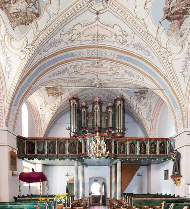 Zdjęcie nr 15: Kościół orientowany, murowany z kamienia, jednonawowy, z prostokątną, trójprzęsłową nawą oraz węższym dwuprzęsłowym prezbiterium zamkniętym prosto, z prostokątną zakrystią przy północnej ścianie. Od zachodu wieża na planie kwadratu, do północnej ściany nawy dobudowana kaplica na rzucie kwadratu o ściętych narożach, do południowej niewielka kruchta na planie kwadratu. Prezbiterium nakryte sklepieniem krzyżowo-żebrowym z dwoma zwornikami. 
Nawa sklepiona krzyżowo, przęsła wydzielone arkadami wspartymi na półfilarach. Otwór tęczowy w formie stojącego prostokąta zamkniętego łukiem półkolistym. W zachodniej części nawy parapet chóru muzycznego, z wybrzuszoną środkową częścią balustrady, wsparty na czterech kolumnach. 
Fasada wieżowa, z wejściem na osi. Wieża smukła, bez podziałów architektonicznych, zakończona profilowanym gzymsem, wyłamującym się na każdej ścianie na kształt łuku odcinkowego. W najwyższej partii ścian, z trzech stron, okna w formie stojącego prostokąta zamkniętego półkoliście. Wieża zwieńczona hełmem baniastym z latarnią, pokrytym gontem. 
Kościół opięty szkarpami dwuuskokowymi, nakrytymi daszkami gontowymi. W elewacji południowej pomiędzy szkarpami pięć wąskich okien w formie stojącego prostokąta zamkniętego łukiem półkolistym. Na wschodniej dobudowany ogrojec w formie masywnej arkady, zamkniętej dwuspadowym daszkiem z ołtarzem i krucyfiksem. Nawa i prezbiterium nakryte osobnymi dachami dwuspadowymi, gontowymi. Nad prezbiterium drewniana wieżyczka na sygnaturkę, z latarnią, zwieńczona hełmem baniastym. Kaplica przykryta dachem gontowych, trójspadowym, kruchta zaś pulpitowym. 
Kościół otoczony niskim murem kamiennym, nakrytym daszkiem gontowym. Od wschodu dwie bramy flankowane filarami z wazonami. 

