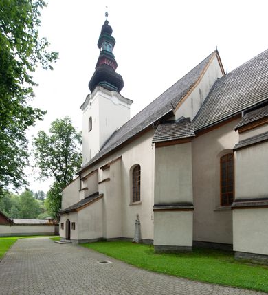 Zdjęcie nr 2: Kościół orientowany, murowany z kamienia, jednonawowy, z prostokątną, trójprzęsłową nawą oraz węższym dwuprzęsłowym prezbiterium zamkniętym prosto, z prostokątną zakrystią przy północnej ścianie. Od zachodu wieża na planie kwadratu, do północnej ściany nawy dobudowana kaplica na rzucie kwadratu o ściętych narożach, do południowej niewielka kruchta na planie kwadratu. Prezbiterium nakryte sklepieniem krzyżowo-żebrowym z dwoma zwornikami. 
Nawa sklepiona krzyżowo, przęsła wydzielone arkadami wspartymi na półfilarach. Otwór tęczowy w formie stojącego prostokąta zamkniętego łukiem półkolistym. W zachodniej części nawy parapet chóru muzycznego, z wybrzuszoną środkową częścią balustrady, wsparty na czterech kolumnach. 
Fasada wieżowa, z wejściem na osi. Wieża smukła, bez podziałów architektonicznych, zakończona profilowanym gzymsem, wyłamującym się na każdej ścianie na kształt łuku odcinkowego. W najwyższej partii ścian, z trzech stron, okna w formie stojącego prostokąta zamkniętego półkoliście. Wieża zwieńczona hełmem baniastym z latarnią, pokrytym gontem. 
Kościół opięty szkarpami dwuuskokowymi, nakrytymi daszkami gontowymi. W elewacji południowej pomiędzy szkarpami pięć wąskich okien w formie stojącego prostokąta zamkniętego łukiem półkolistym. Na wschodniej dobudowany ogrojec w formie masywnej arkady, zamkniętej dwuspadowym daszkiem z ołtarzem i krucyfiksem. Nawa i prezbiterium nakryte osobnymi dachami dwuspadowymi, gontowymi. Nad prezbiterium drewniana wieżyczka na sygnaturkę, z latarnią, zwieńczona hełmem baniastym. Kaplica przykryta dachem gontowych, trójspadowym, kruchta zaś pulpitowym. 
Kościół otoczony niskim murem kamiennym, nakrytym daszkiem gontowym. Od wschodu dwie bramy flankowane filarami z wazonami. 

