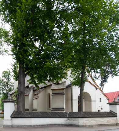 Zdjęcie nr 29: Kościół orientowany, murowany z kamienia, jednonawowy, z prostokątną, trójprzęsłową nawą oraz węższym dwuprzęsłowym prezbiterium zamkniętym prosto, z prostokątną zakrystią przy północnej ścianie. Od zachodu wieża na planie kwadratu, do północnej ściany nawy dobudowana kaplica na rzucie kwadratu o ściętych narożach, do południowej niewielka kruchta na planie kwadratu. Prezbiterium nakryte sklepieniem krzyżowo-żebrowym z dwoma zwornikami. 
Nawa sklepiona krzyżowo, przęsła wydzielone arkadami wspartymi na półfilarach. Otwór tęczowy w formie stojącego prostokąta zamkniętego łukiem półkolistym. W zachodniej części nawy parapet chóru muzycznego, z wybrzuszoną środkową częścią balustrady, wsparty na czterech kolumnach. 
Fasada wieżowa, z wejściem na osi. Wieża smukła, bez podziałów architektonicznych, zakończona profilowanym gzymsem, wyłamującym się na każdej ścianie na kształt łuku odcinkowego. W najwyższej partii ścian, z trzech stron, okna w formie stojącego prostokąta zamkniętego półkoliście. Wieża zwieńczona hełmem baniastym z latarnią, pokrytym gontem. 
Kościół opięty szkarpami dwuuskokowymi, nakrytymi daszkami gontowymi. W elewacji południowej pomiędzy szkarpami pięć wąskich okien w formie stojącego prostokąta zamkniętego łukiem półkolistym. Na wschodniej dobudowany ogrojec w formie masywnej arkady, zamkniętej dwuspadowym daszkiem z ołtarzem i krucyfiksem. Nawa i prezbiterium nakryte osobnymi dachami dwuspadowymi, gontowymi. Nad prezbiterium drewniana wieżyczka na sygnaturkę, z latarnią, zwieńczona hełmem baniastym. Kaplica przykryta dachem gontowych, trójspadowym, kruchta zaś pulpitowym. 
Kościół otoczony niskim murem kamiennym, nakrytym daszkiem gontowym. Od wschodu dwie bramy flankowane filarami z wazonami. 

