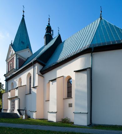 Zdjęcie nr 18: Kościół orientowany, jednonawowy, z krótkim zakończonym wielobocznie prezbiterium, przy którym od północy zakrystia z nowszym przedsionkiem; przy nawie od północy prostokątna kaplica Różańcowa (1712 r.), od zachodu wieża na rzucie kwadratu, od południa drewniana kruchta. Wewnątrz stropy. Arkada tęczy szeroka półkolista. Zewnątrz mury opięte przyporami, tynkowane. Dachy dwuspadowe i pulpitowe. Na kalenicy dachu nawy wieżyczka na sygnaturkę z datą 1878. Okna prostokątne zamknięte półkoliście. Dwa portale kamienne prostokątne. Wieża dołem gotycka, nadbudowana w stylu pseudoromańskim; trójkondygnacyjna, dołem z narożnikami artykułowanymi boniowaniem, narożniki górnej kondygnacji ujęte lizenami połączonymi fryzem arkadkowym. Elewacje wieży zwieńczone trójkątnymi szczytami i ostrosłupowym hełmem krytym blachą.