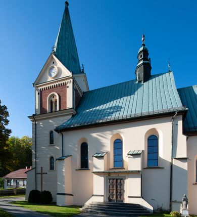 Zdjęcie nr 16: Kościół orientowany, jednonawowy, z krótkim zakończonym wielobocznie prezbiterium, przy którym od północy zakrystia z nowszym przedsionkiem; przy nawie od północy prostokątna kaplica Różańcowa (1712 r.), od zachodu wieża na rzucie kwadratu, od południa drewniana kruchta. Wewnątrz stropy. Arkada tęczy szeroka półkolista. Zewnątrz mury opięte przyporami, tynkowane. Dachy dwuspadowe i pulpitowe. Na kalenicy dachu nawy wieżyczka na sygnaturkę z datą 1878. Okna prostokątne zamknięte półkoliście. Dwa portale kamienne prostokątne. Wieża dołem gotycka, nadbudowana w stylu pseudoromańskim; trójkondygnacyjna, dołem z narożnikami artykułowanymi boniowaniem, narożniki górnej kondygnacji ujęte lizenami połączonymi fryzem arkadkowym. Elewacje wieży zwieńczone trójkątnymi szczytami i ostrosłupowym hełmem krytym blachą.