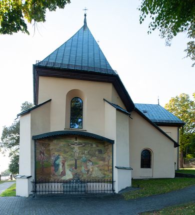 Zdjęcie nr 5: Kościół orientowany, jednonawowy, z krótkim zakończonym wielobocznie prezbiterium, przy którym od północy zakrystia z nowszym przedsionkiem; przy nawie od północy prostokątna kaplica Różańcowa (1712 r.), od zachodu wieża na rzucie kwadratu, od południa drewniana kruchta. Wewnątrz stropy. Arkada tęczy szeroka półkolista. Zewnątrz mury opięte przyporami, tynkowane. Dachy dwuspadowe i pulpitowe. Na kalenicy dachu nawy wieżyczka na sygnaturkę z datą 1878. Okna prostokątne zamknięte półkoliście. Dwa portale kamienne prostokątne. Wieża dołem gotycka, nadbudowana w stylu pseudoromańskim; trójkondygnacyjna, dołem z narożnikami artykułowanymi boniowaniem, narożniki górnej kondygnacji ujęte lizenami połączonymi fryzem arkadkowym. Elewacje wieży zwieńczone trójkątnymi szczytami i ostrosłupowym hełmem krytym blachą.