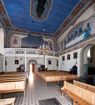 Zdjęcie nr 15: Kościół orientowany, jednonawowy, z krótkim zakończonym wielobocznie prezbiterium, przy którym od północy zakrystia z nowszym przedsionkiem; przy nawie od północy prostokątna kaplica Różańcowa (1712 r.), od zachodu wieża na rzucie kwadratu, od południa drewniana kruchta. Wewnątrz stropy. Arkada tęczy szeroka półkolista. Zewnątrz mury opięte przyporami, tynkowane. Dachy dwuspadowe i pulpitowe. Na kalenicy dachu nawy wieżyczka na sygnaturkę z datą 1878. Okna prostokątne zamknięte półkoliście. Dwa portale kamienne prostokątne. Wieża dołem gotycka, nadbudowana w stylu pseudoromańskim; trójkondygnacyjna, dołem z narożnikami artykułowanymi boniowaniem, narożniki górnej kondygnacji ujęte lizenami połączonymi fryzem arkadkowym. Elewacje wieży zwieńczone trójkątnymi szczytami i ostrosłupowym hełmem krytym blachą.