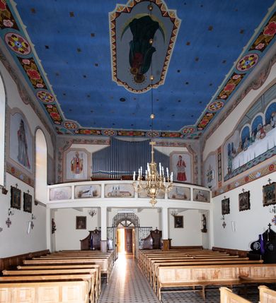 Zdjęcie nr 11: Kościół orientowany, jednonawowy, z krótkim zakończonym wielobocznie prezbiterium, przy którym od północy zakrystia z nowszym przedsionkiem; przy nawie od północy prostokątna kaplica Różańcowa (1712 r.), od zachodu wieża na rzucie kwadratu, od południa drewniana kruchta. Wewnątrz stropy. Arkada tęczy szeroka półkolista. Zewnątrz mury opięte przyporami, tynkowane. Dachy dwuspadowe i pulpitowe. Na kalenicy dachu nawy wieżyczka na sygnaturkę z datą 1878. Okna prostokątne zamknięte półkoliście. Dwa portale kamienne prostokątne. Wieża dołem gotycka, nadbudowana w stylu pseudoromańskim; trójkondygnacyjna, dołem z narożnikami artykułowanymi boniowaniem, narożniki górnej kondygnacji ujęte lizenami połączonymi fryzem arkadkowym. Elewacje wieży zwieńczone trójkątnymi szczytami i ostrosłupowym hełmem krytym blachą.