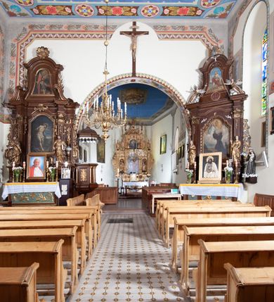 Zdjęcie nr 7: Kościół orientowany, jednonawowy, z krótkim zakończonym wielobocznie prezbiterium, przy którym od północy zakrystia z nowszym przedsionkiem; przy nawie od północy prostokątna kaplica Różańcowa (1712 r.), od zachodu wieża na rzucie kwadratu, od południa drewniana kruchta. Wewnątrz stropy. Arkada tęczy szeroka półkolista. Zewnątrz mury opięte przyporami, tynkowane. Dachy dwuspadowe i pulpitowe. Na kalenicy dachu nawy wieżyczka na sygnaturkę z datą 1878. Okna prostokątne zamknięte półkoliście. Dwa portale kamienne prostokątne. Wieża dołem gotycka, nadbudowana w stylu pseudoromańskim; trójkondygnacyjna, dołem z narożnikami artykułowanymi boniowaniem, narożniki górnej kondygnacji ujęte lizenami połączonymi fryzem arkadkowym. Elewacje wieży zwieńczone trójkątnymi szczytami i ostrosłupowym hełmem krytym blachą.