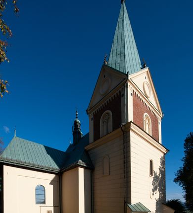 Zdjęcie nr 22: Kościół orientowany, jednonawowy, z krótkim zakończonym wielobocznie prezbiterium, przy którym od północy zakrystia z nowszym przedsionkiem; przy nawie od północy prostokątna kaplica Różańcowa (1712 r.), od zachodu wieża na rzucie kwadratu, od południa drewniana kruchta. Wewnątrz stropy. Arkada tęczy szeroka półkolista. Zewnątrz mury opięte przyporami, tynkowane. Dachy dwuspadowe i pulpitowe. Na kalenicy dachu nawy wieżyczka na sygnaturkę z datą 1878. Okna prostokątne zamknięte półkoliście. Dwa portale kamienne prostokątne. Wieża dołem gotycka, nadbudowana w stylu pseudoromańskim; trójkondygnacyjna, dołem z narożnikami artykułowanymi boniowaniem, narożniki górnej kondygnacji ujęte lizenami połączonymi fryzem arkadkowym. Elewacje wieży zwieńczone trójkątnymi szczytami i ostrosłupowym hełmem krytym blachą.